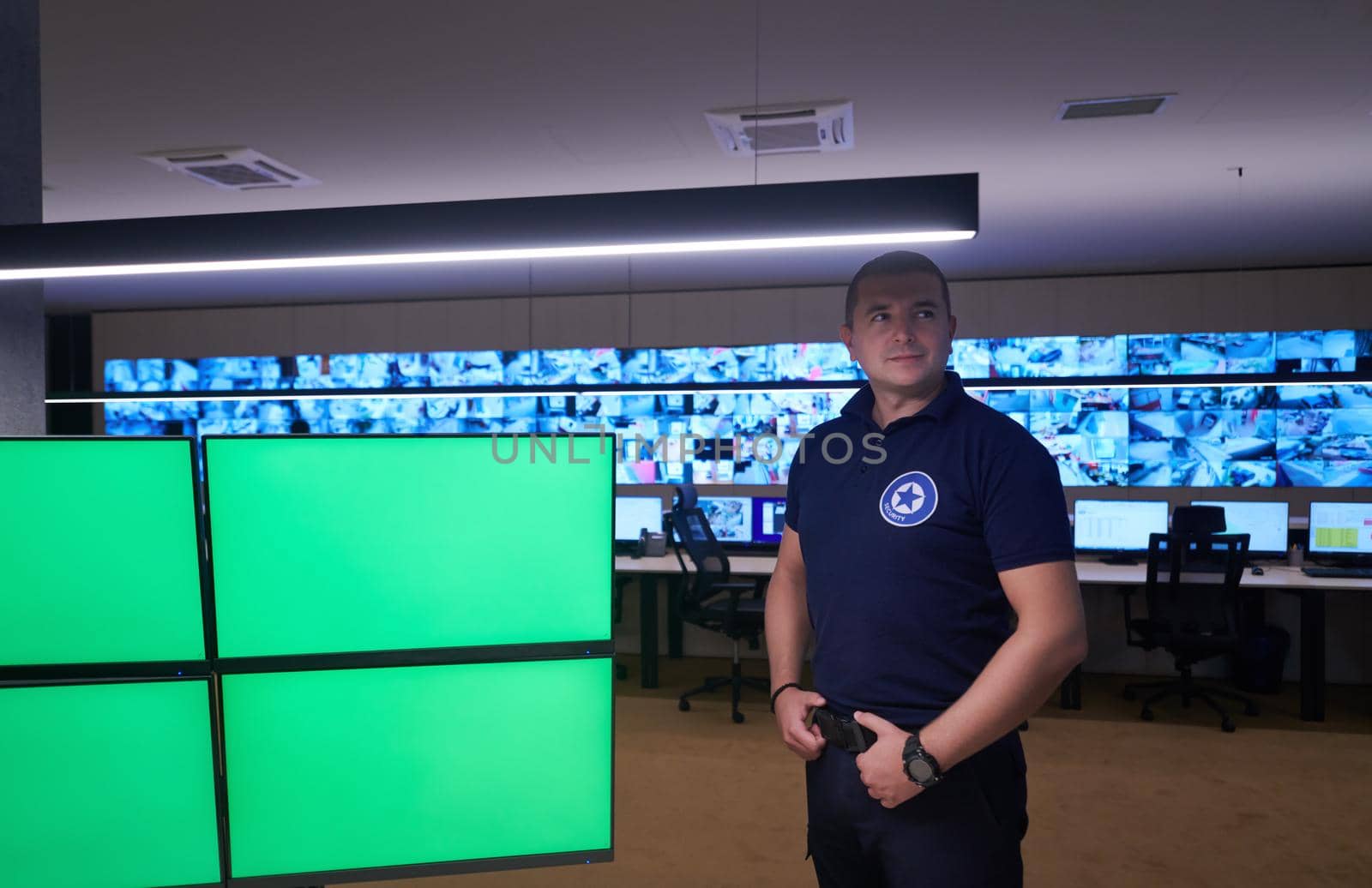 portrait of young male security operator working in a data system control room Working at workstation with multiple displays, security guard working on multiple monitors  Male computer operator monitoring from a security center