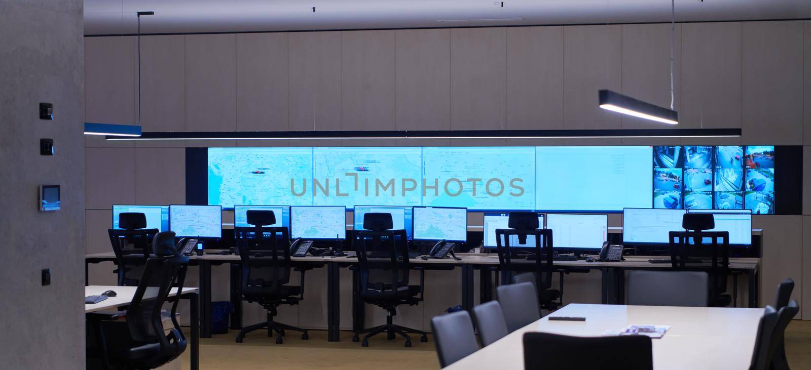 Empty interior of big modern security system control room, workstation with multiple displays, monitoring room with at security data center  Empty office, desk, and chairs at a main CCTV security data center