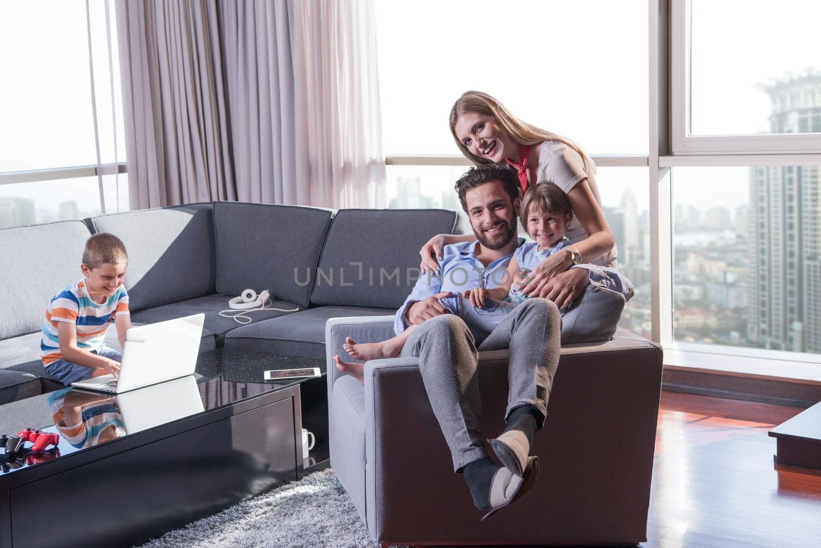 happy couple spending time with kids using tablet computer on an armchair  at home