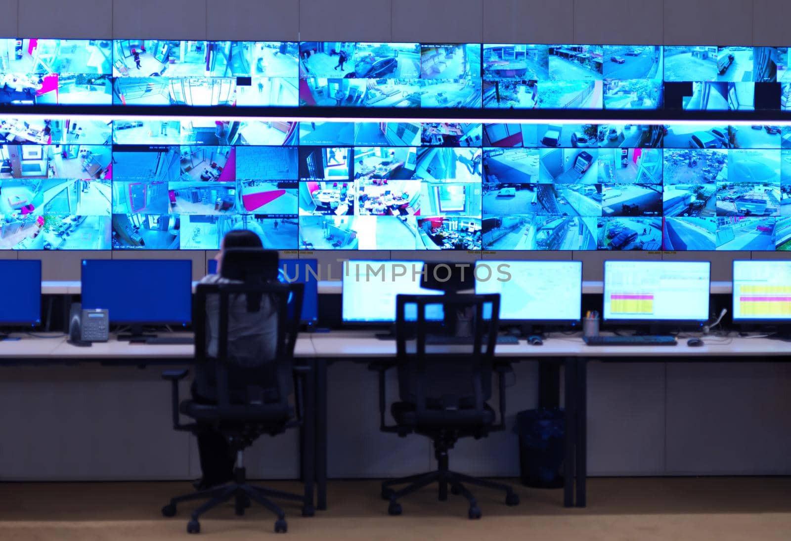 Female security operator working in a data system control room offices Technical Operator Working at  workstation with multiple displays, security guard working on multiple monitors