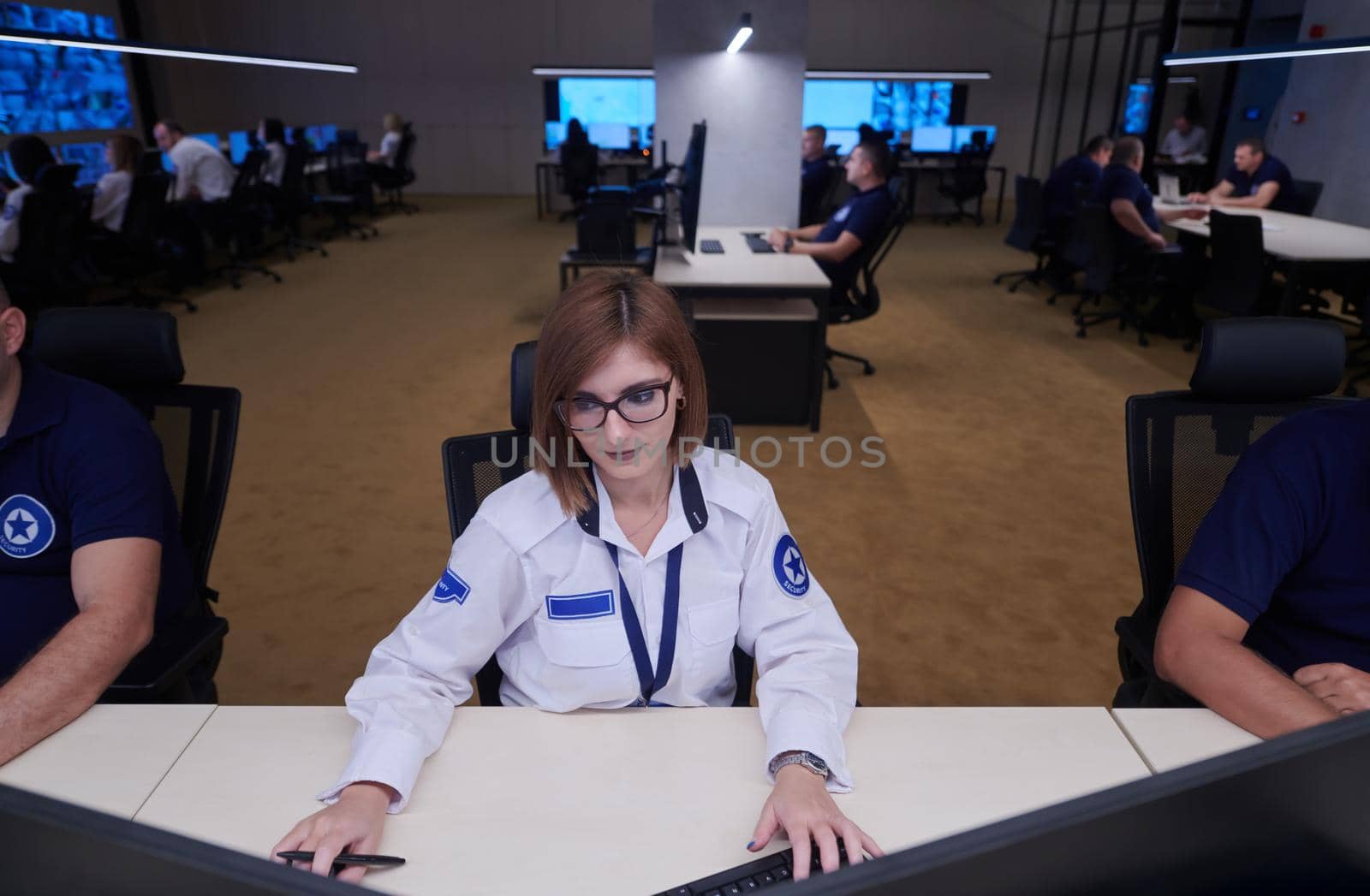 Female security operator working in a data system control room offices Technical Operator Working at  workstation with multiple displays, security guard working on multiple monitors