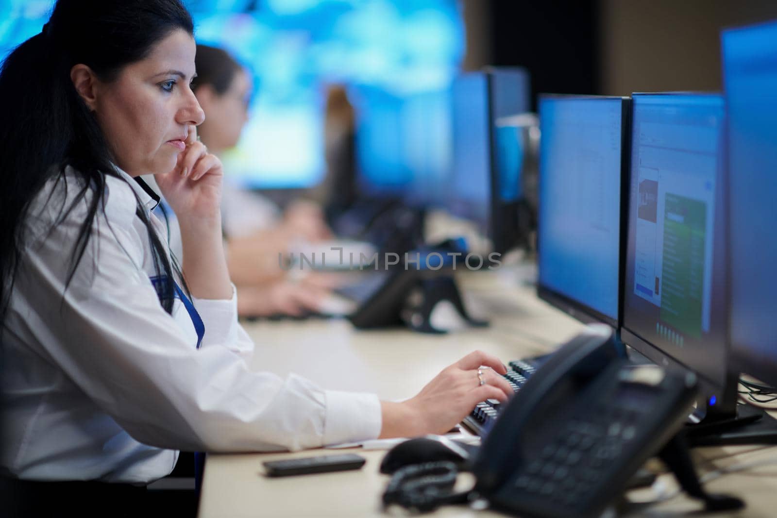 Female security operator working in a data system control room offices Technical Operator Working at  workstation with multiple displays, security guard working on multiple monitors