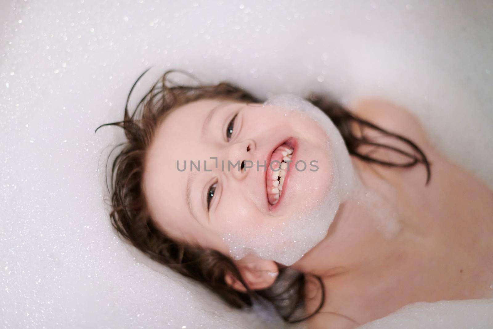 little girl in bath playing with soap foam by dotshock