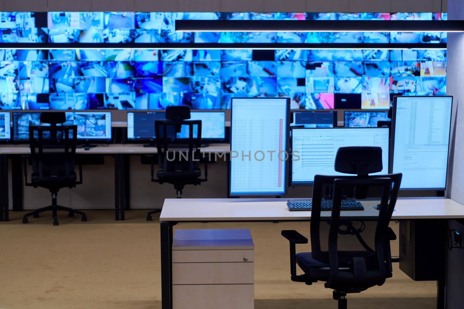 Empty interior of big modern security system control room, workstation with multiple displays, monitoring room with at security data center  Empty office, desk, and chairs at a main CCTV security data center