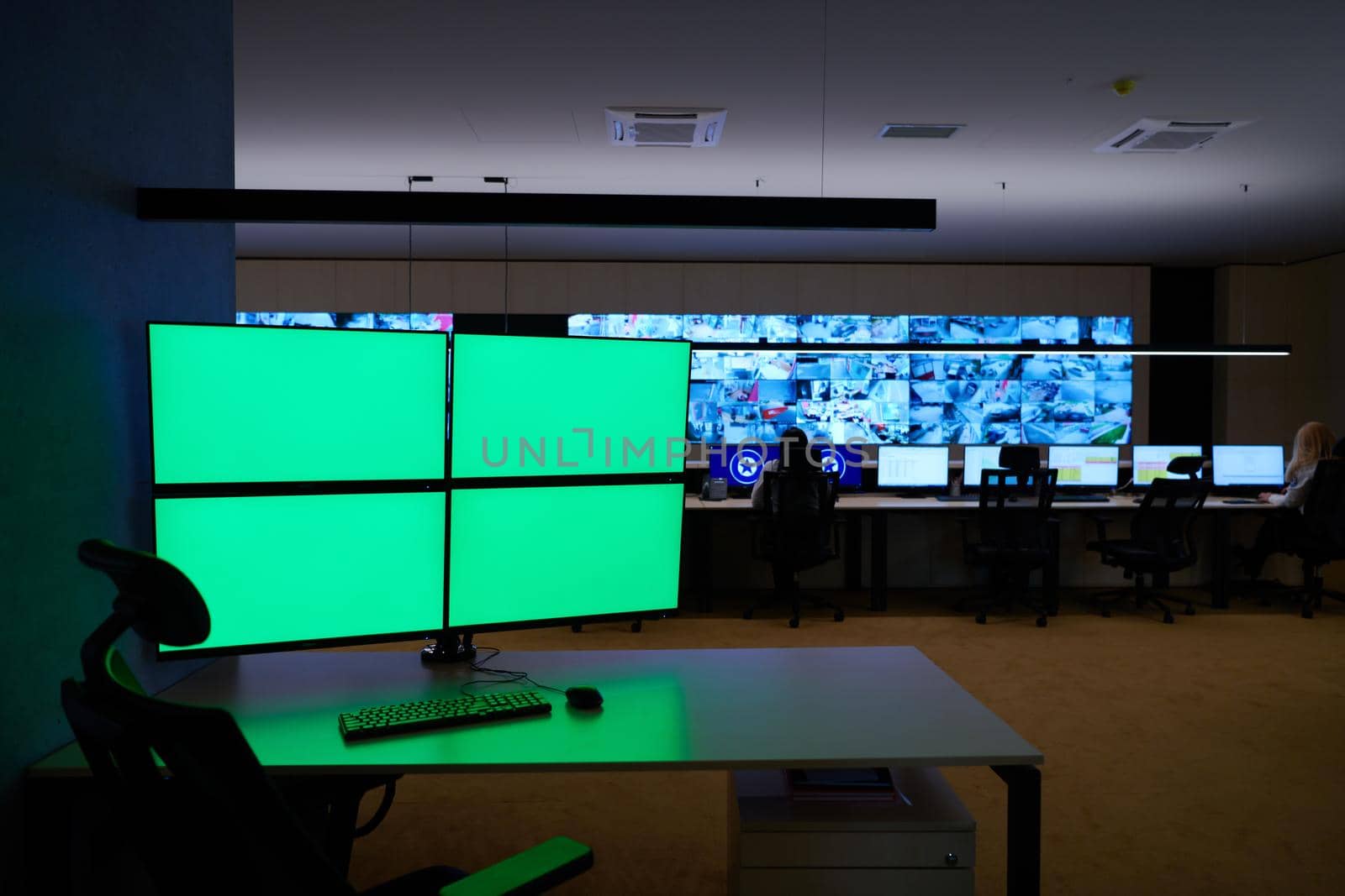 Empty interior of big modern security system control room with blank green screens, workstation with multiple displays, monitoring room with at security data center  Empty office, desk, and chairs at a main CCTV security data center