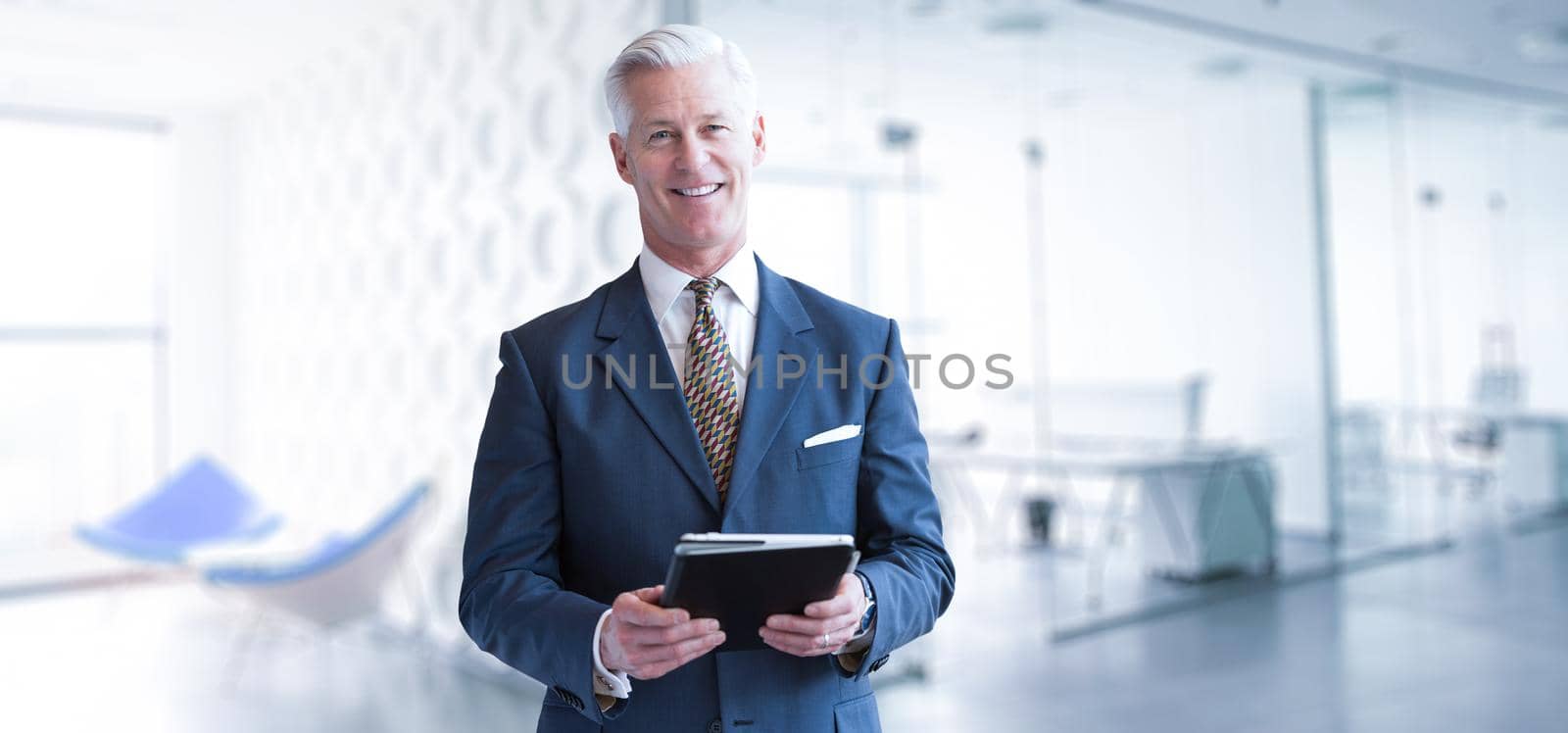 Portrait of senior businessman using tablet in front of his modern office