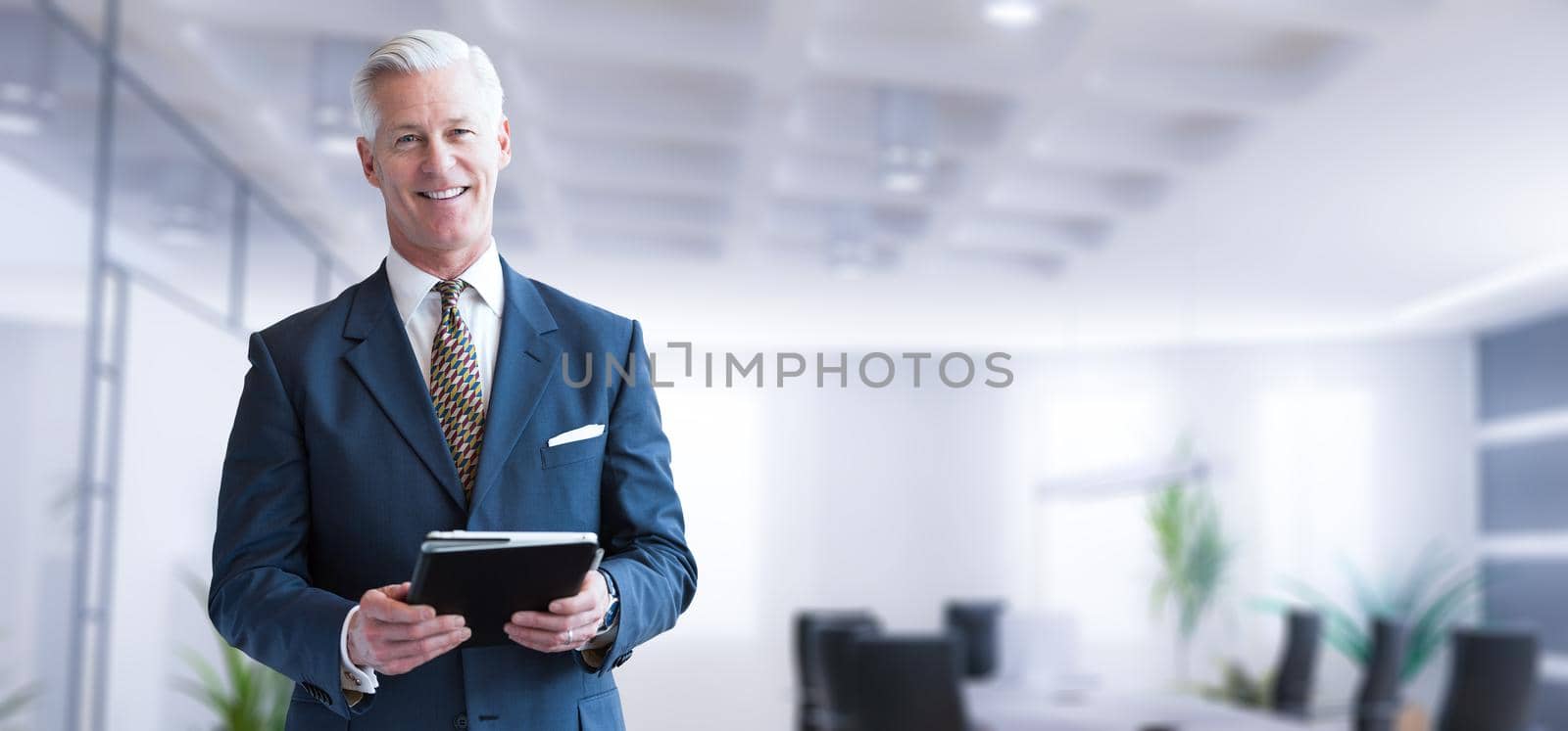 Portrait of senior businessman using tablet in front of his modern office