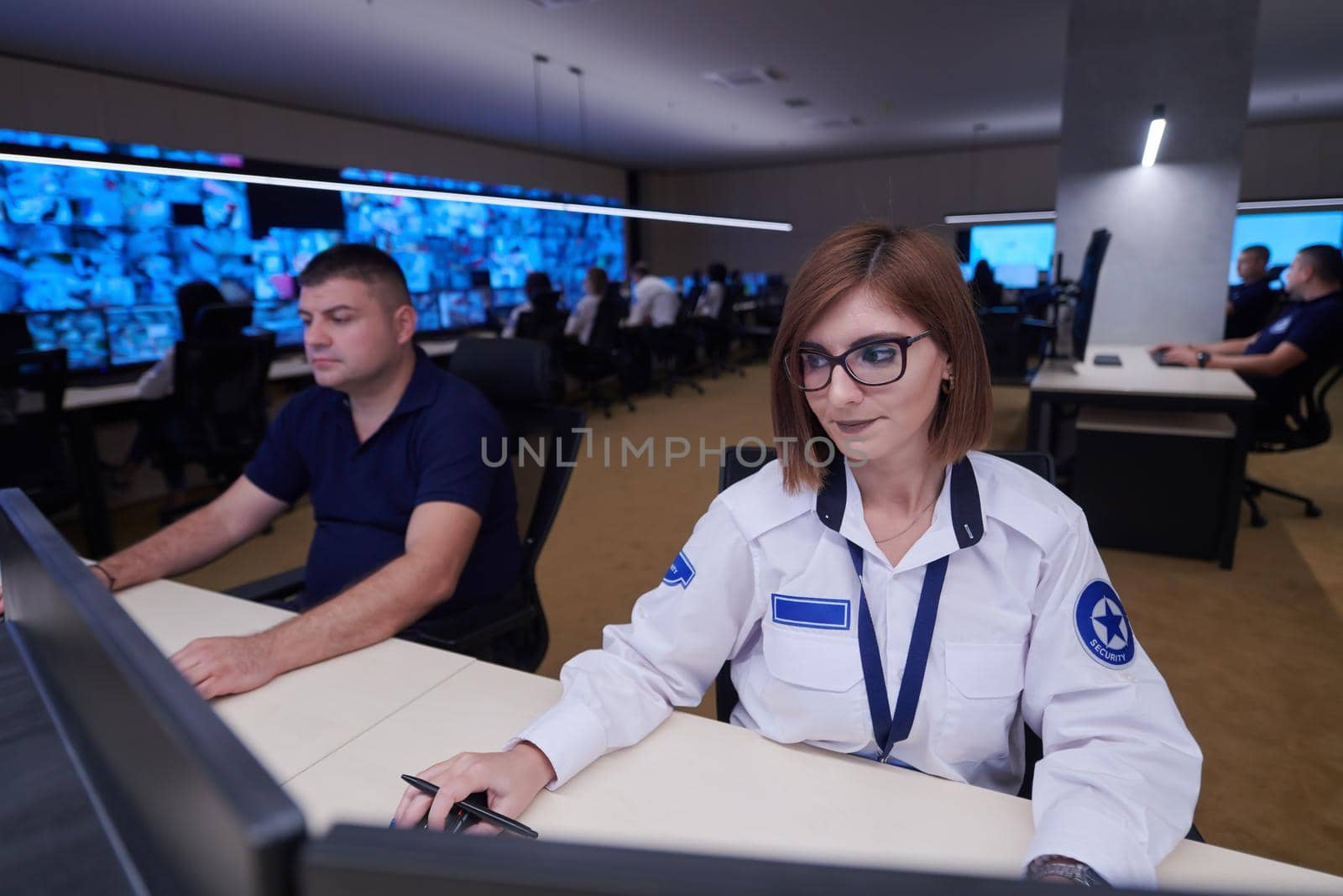 Female security operator working in a data system control room offices Technical Operator Working at  workstation with multiple displays, security guard working on multiple monitors