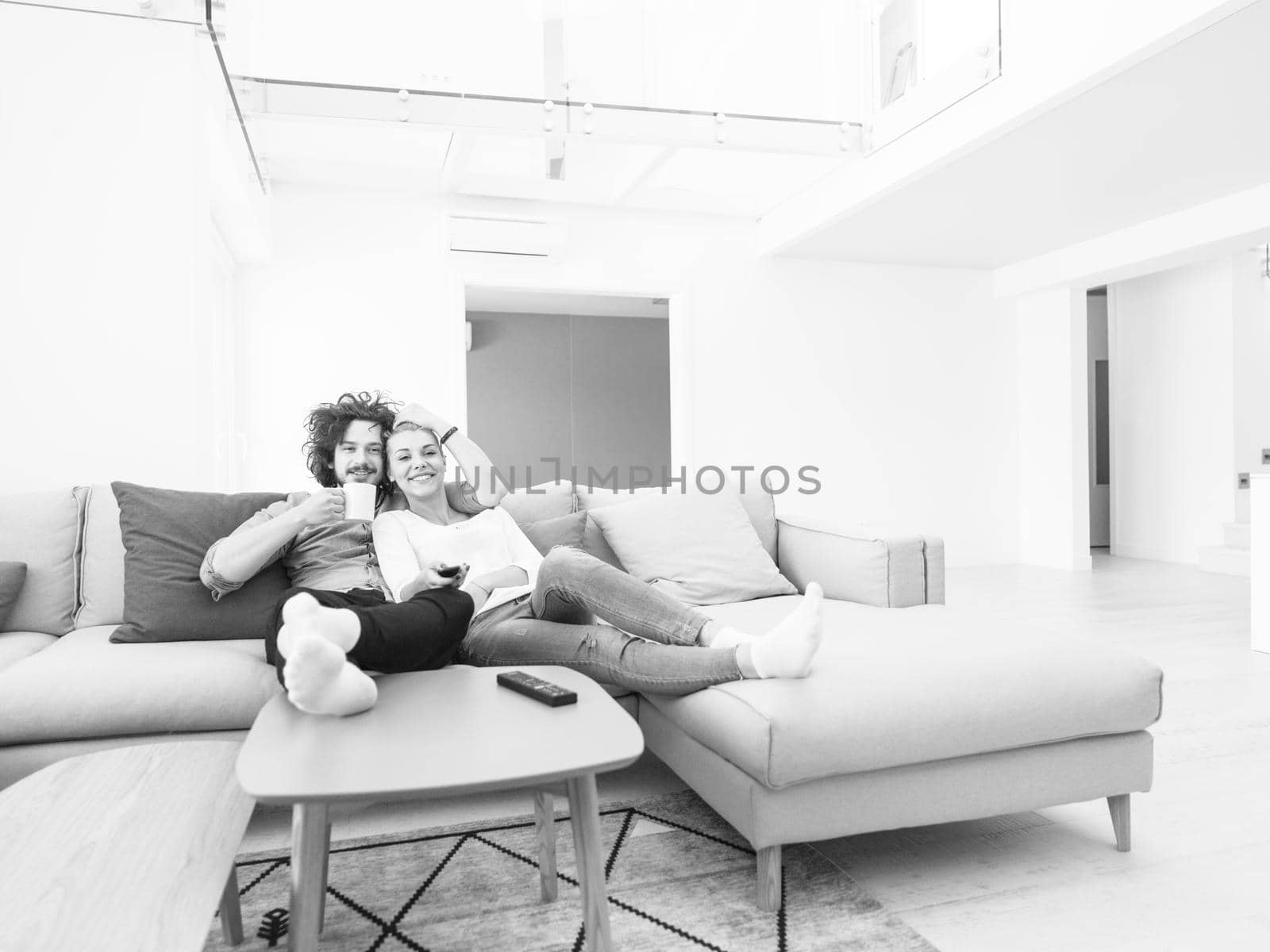 Young couple on the sofa watching television together in their luxury home