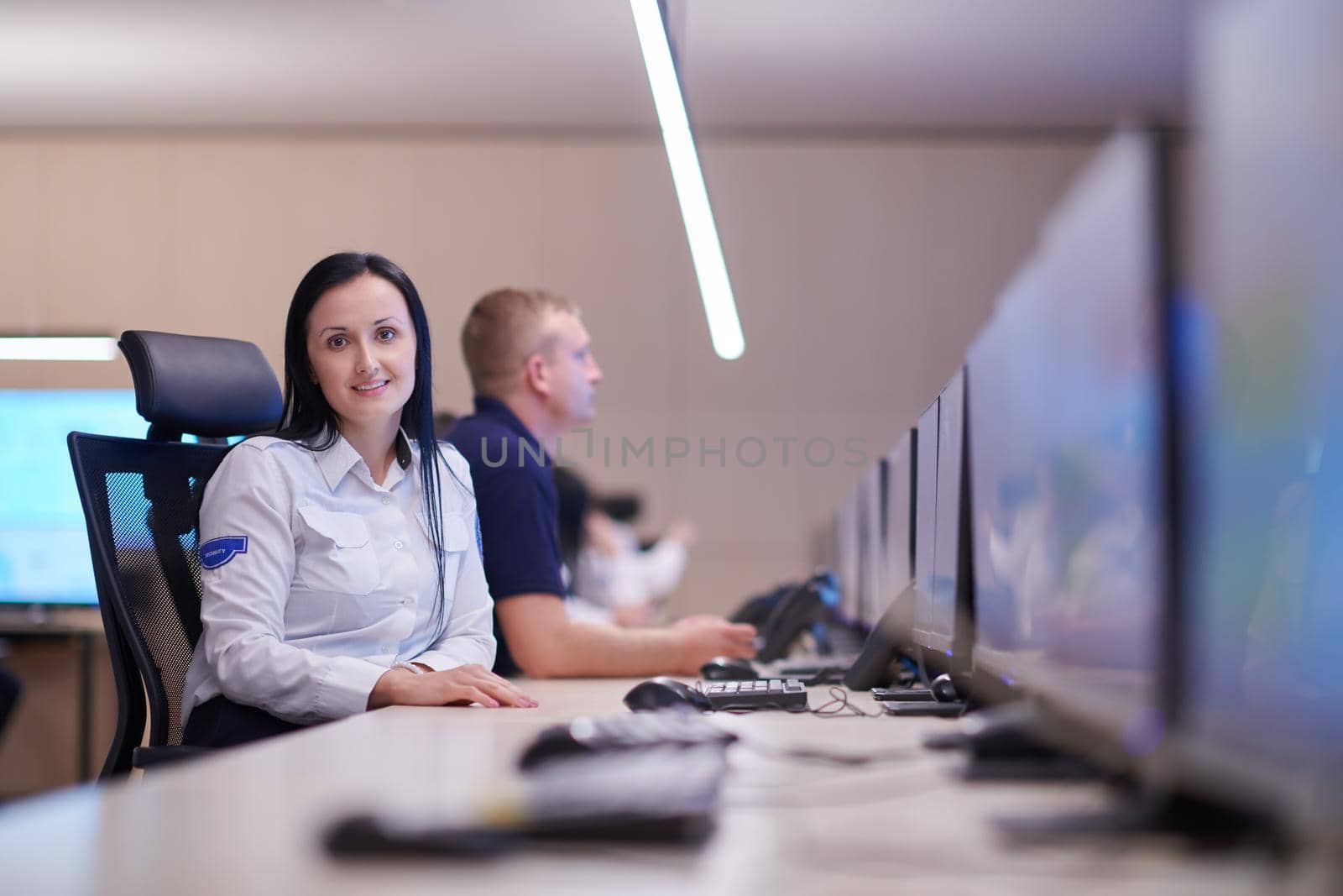 Female security operator working in a data system control room offices Technical Operator Working at  workstation with multiple displays, security guard working on multiple monitors