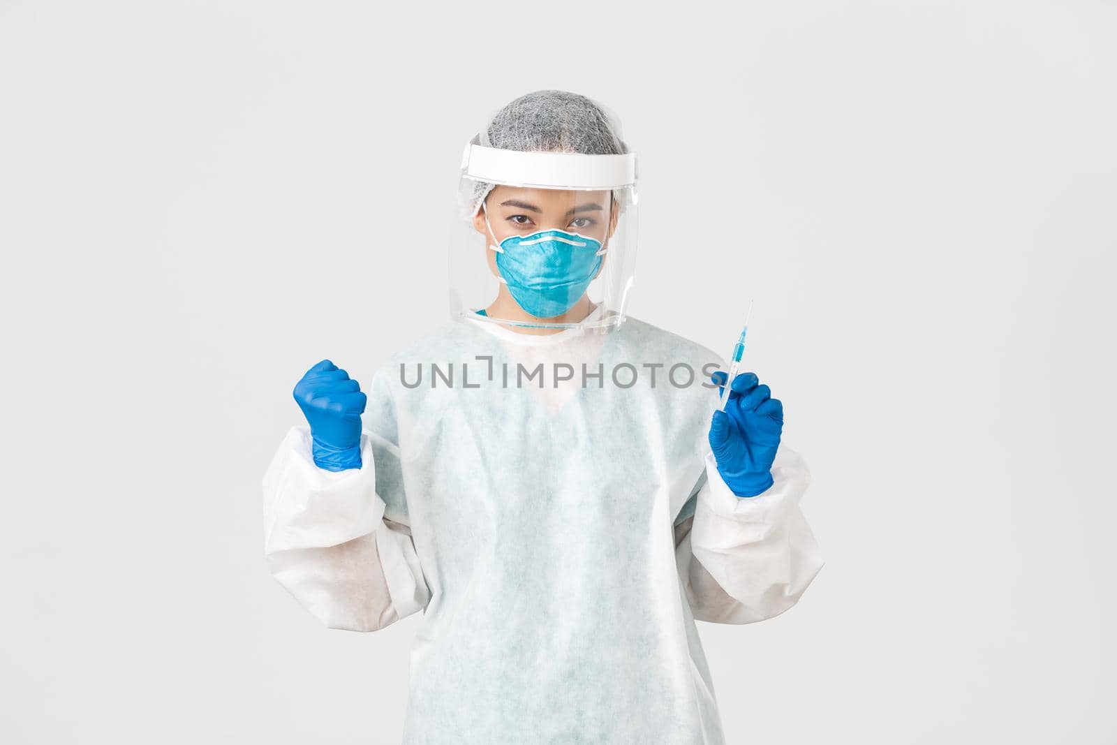 Covid-19, coronavirus disease, healthcare workers concept. Determined and confident female asian doctor, tech lab employee in personal protective equipment holding syringe with vaccine.
