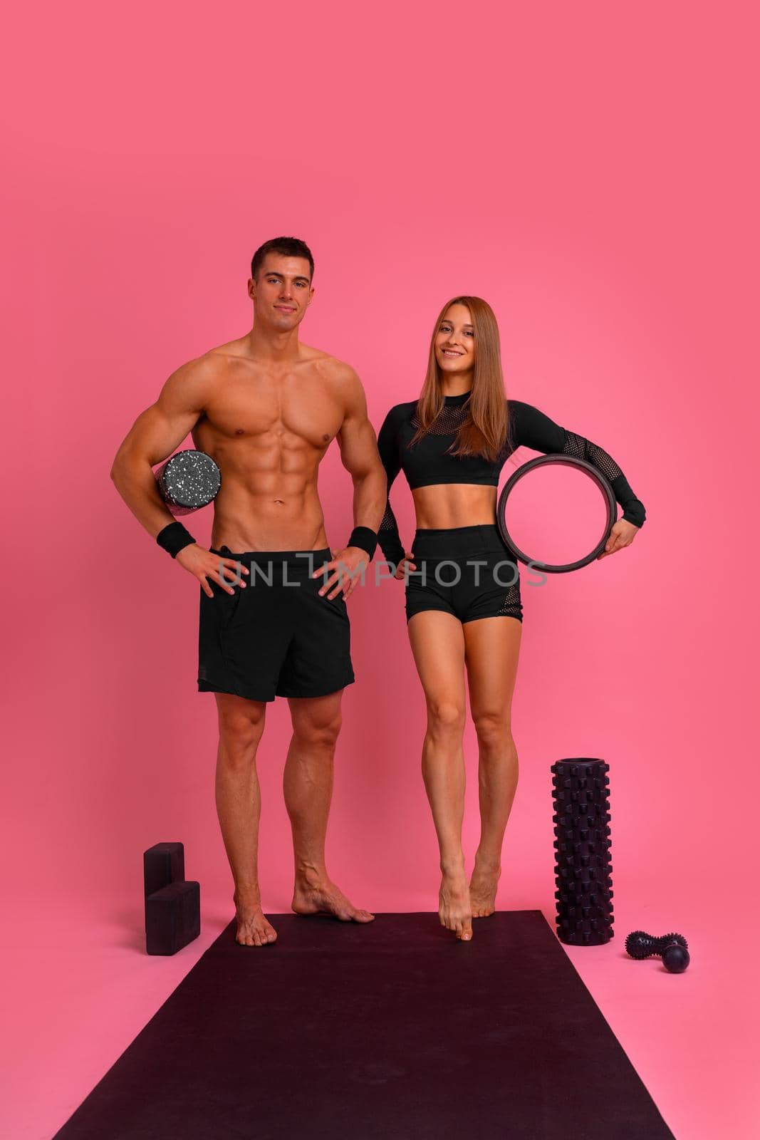 Fit couple at the gym isolated on pink background. Fitness concept. Healthy life style