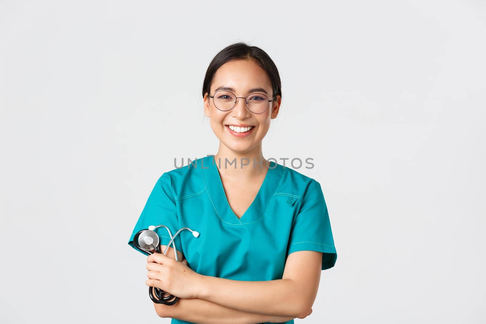 Covid-19, coronavirus disease, healthcare workers concept. Confident happy asian female physician, doctor in glasses, cross arms chest and smiling, holding stethoscope for examination.