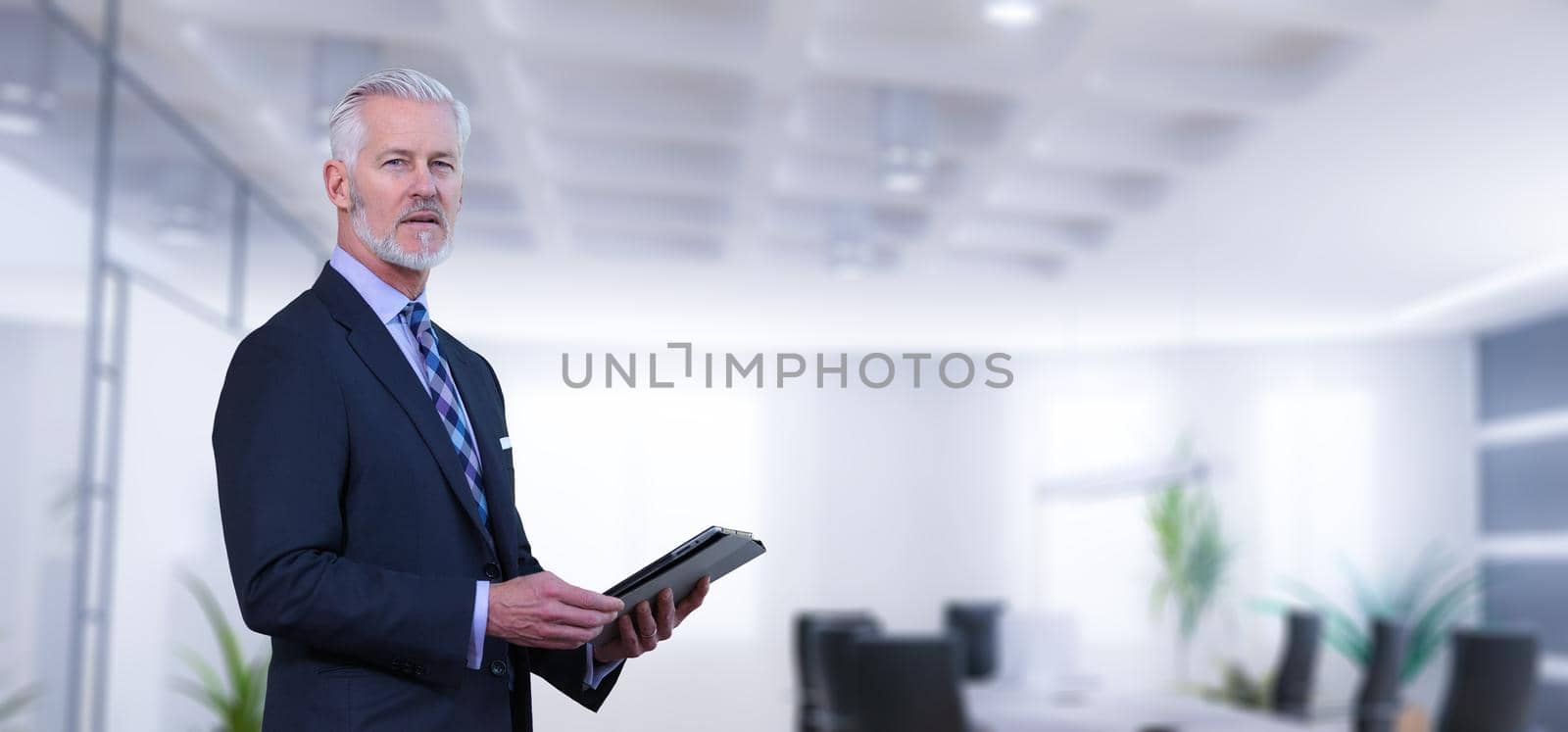 Portrait of senior businessman using tablet in front of his modern office