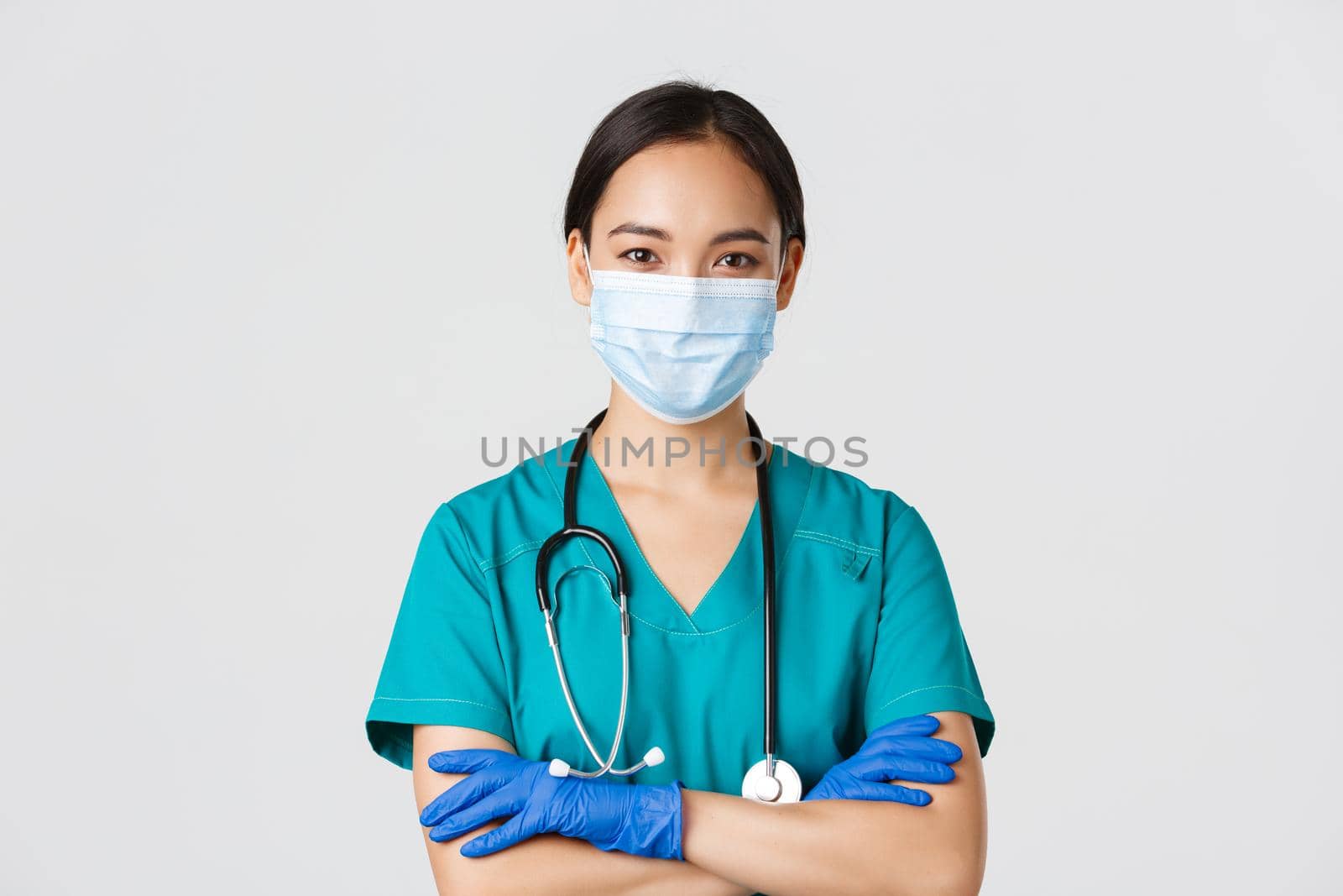 Covid-19, coronavirus disease, healthcare workers concept. Close-up of confident smiling, professional asian doctor, nurse in medical mask and rubber gloves ready for examination, white background by Benzoix