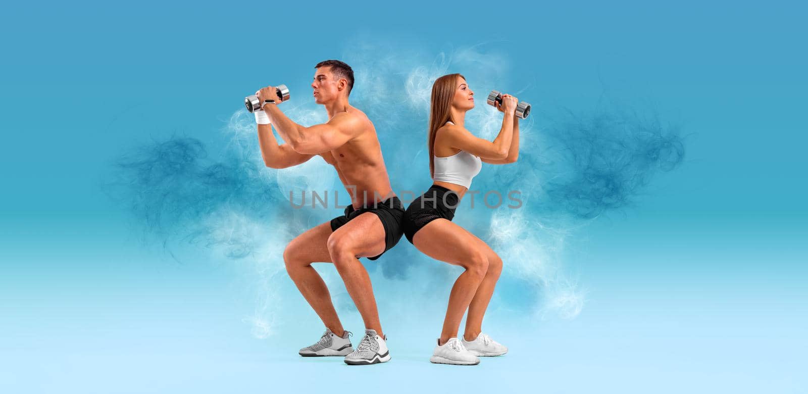 Fit couple at the gym on blue background with dumbbells. Fitness concept. Healthy life style. by MikeOrlov