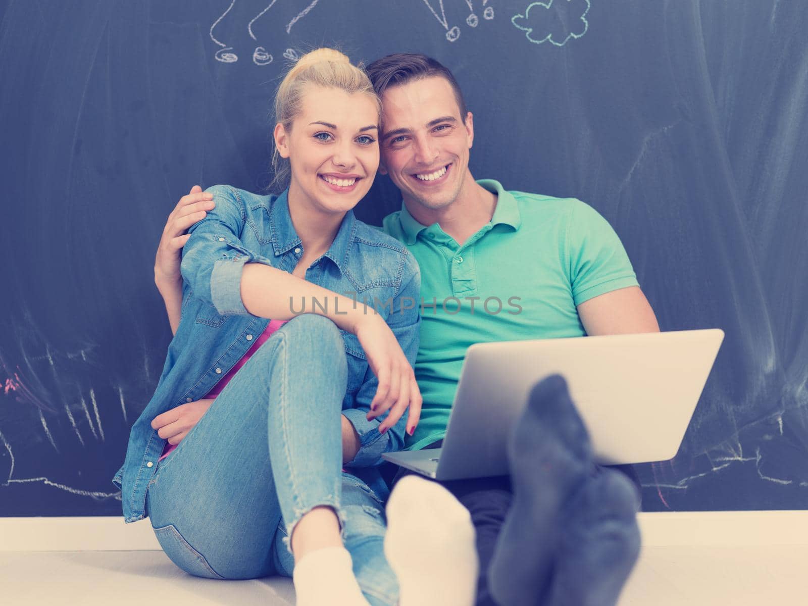couple using laptop in front of gray chalkboard by dotshock