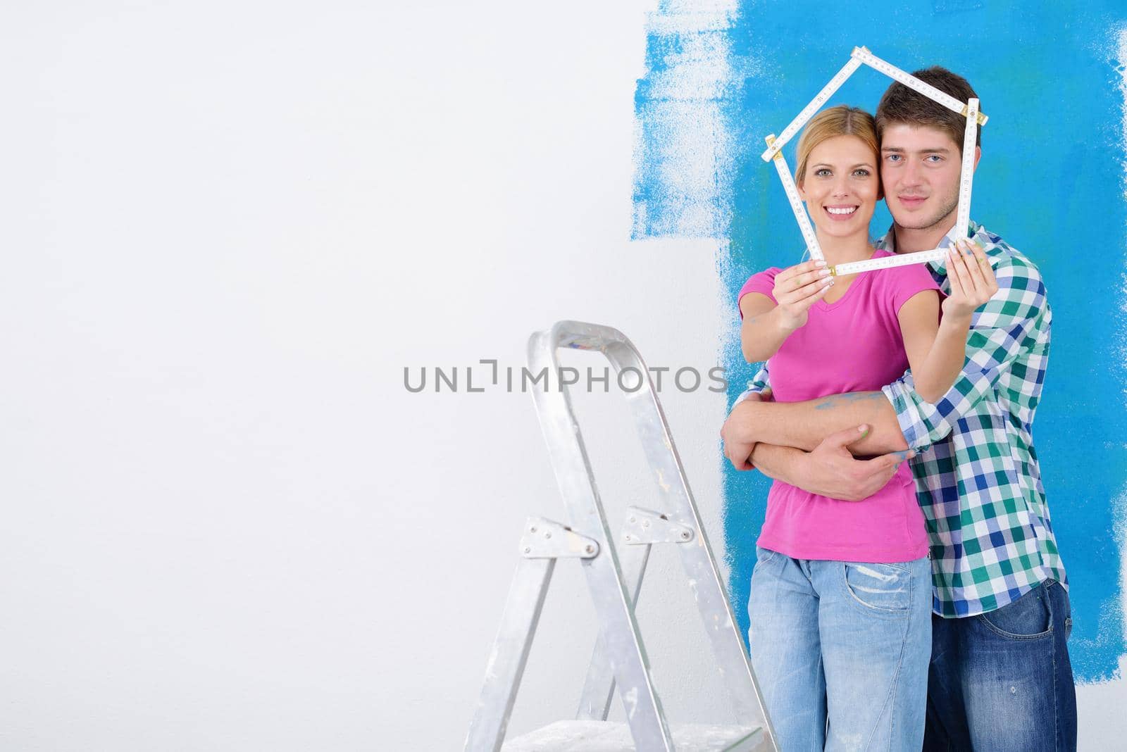 happy young couple paint in green and blue color white wall of their new home