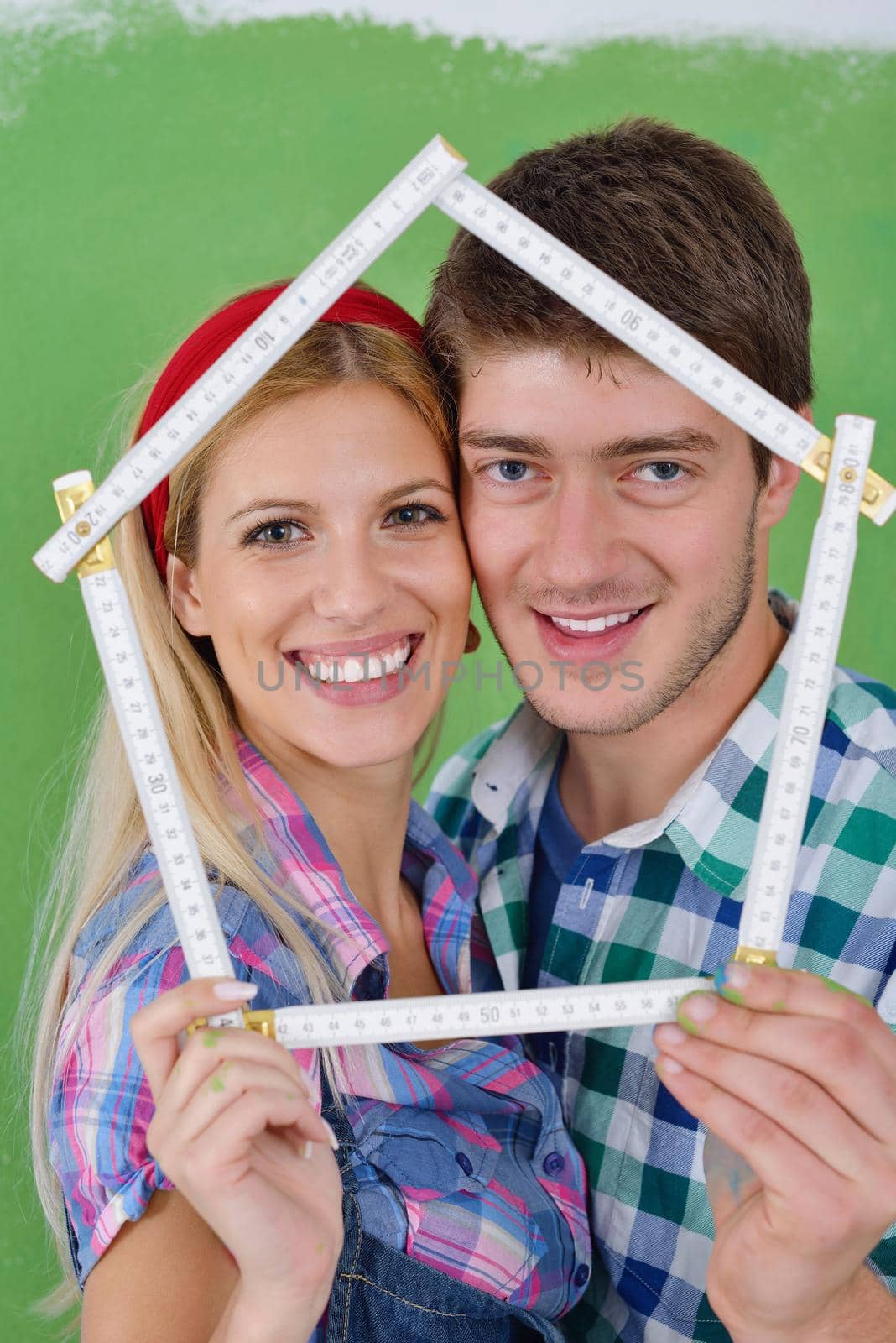 happy young couple paint in green and blue color white wall of their new home