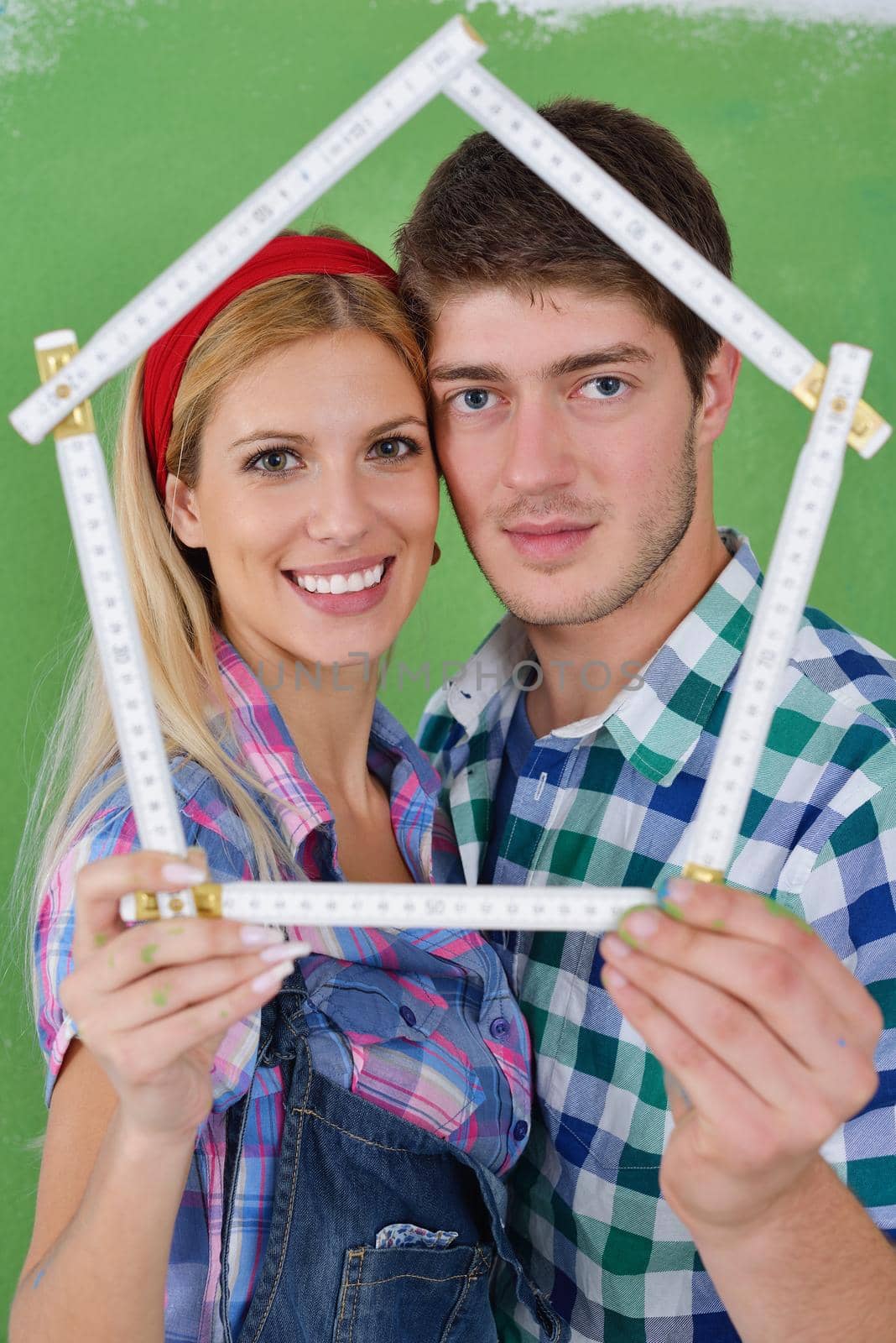 happy young couple paint in green and blue color white wall of their new home