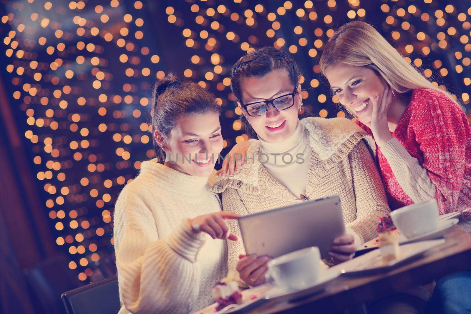happy girls group  looking at a pc tablet in a home interior and have fun