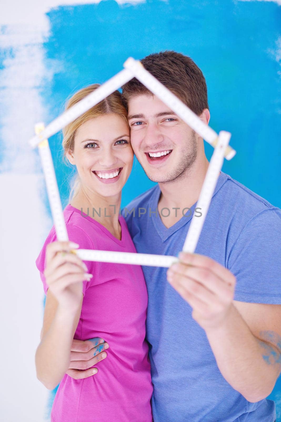 happy young couple paint in green and blue color white wall of their new home