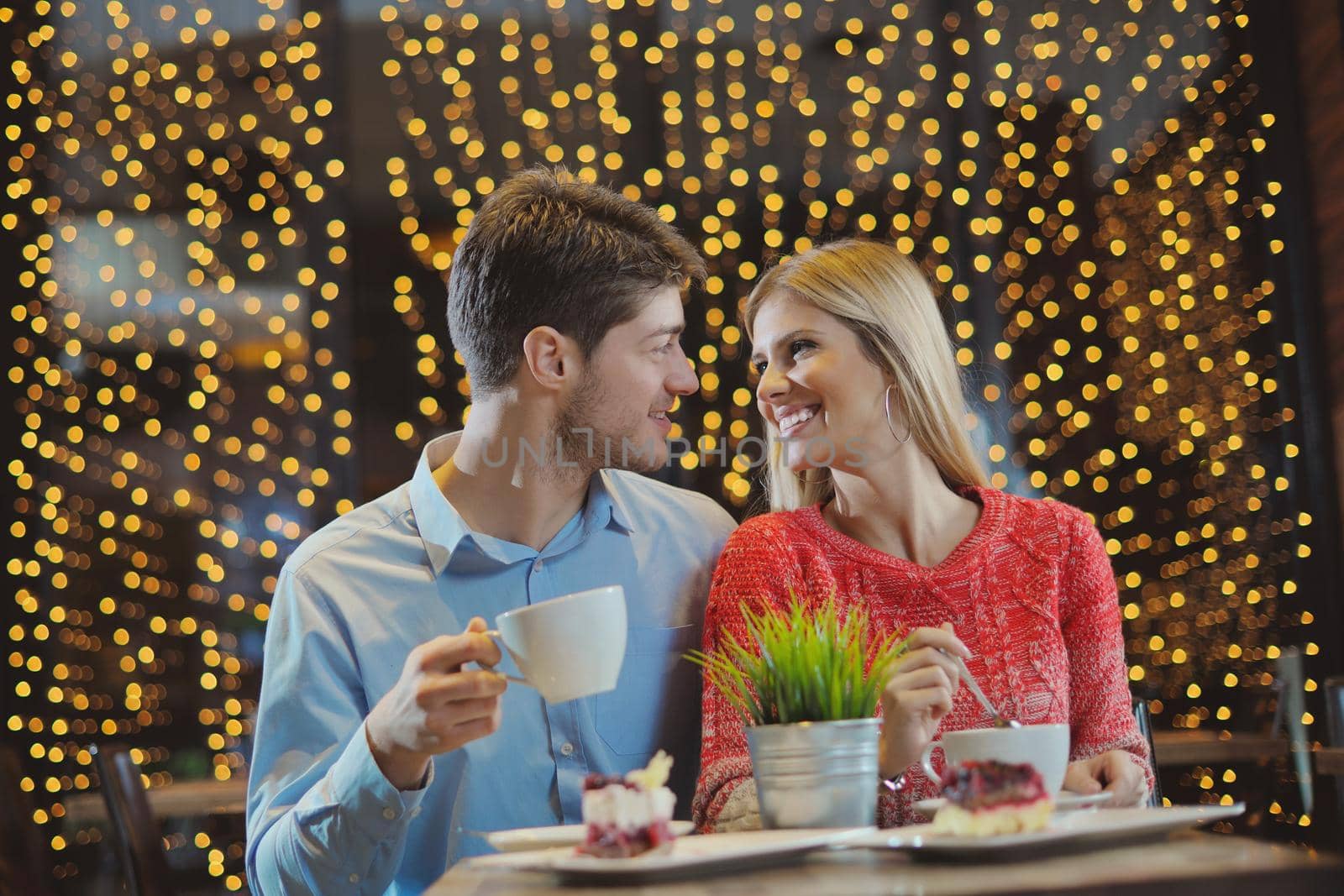 romantic evening date in restaurant  happy young couple with wine glass tea and cake