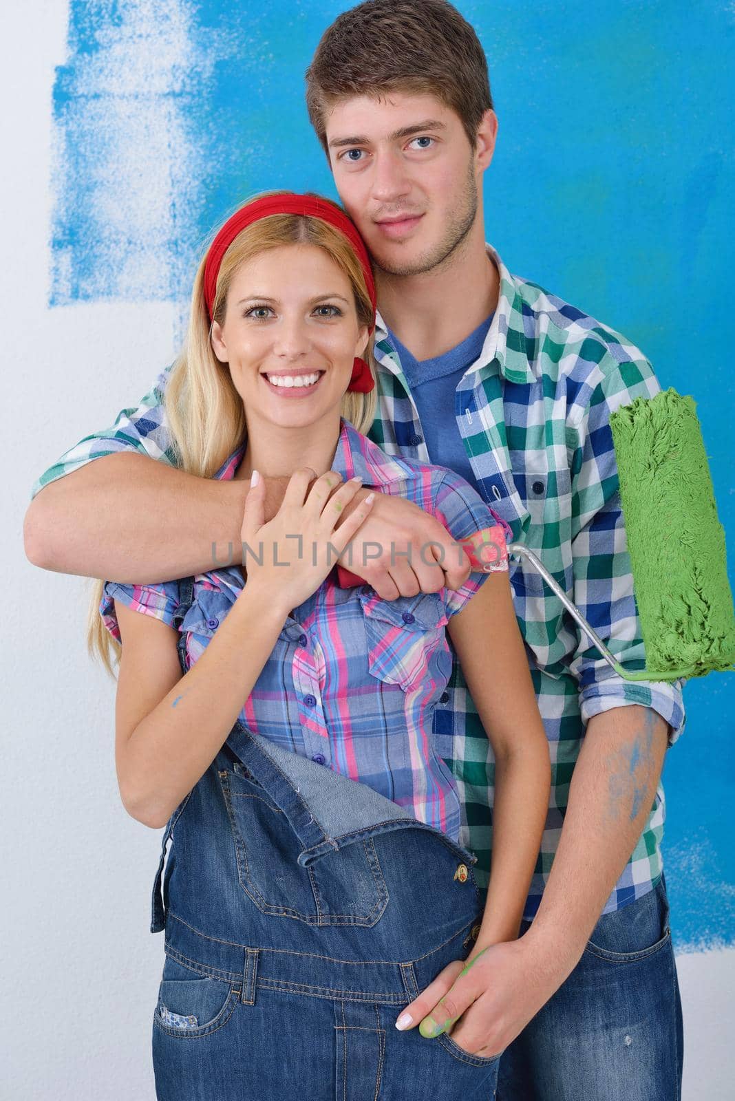 happy young couple paint in green and blue color white wall of their new home