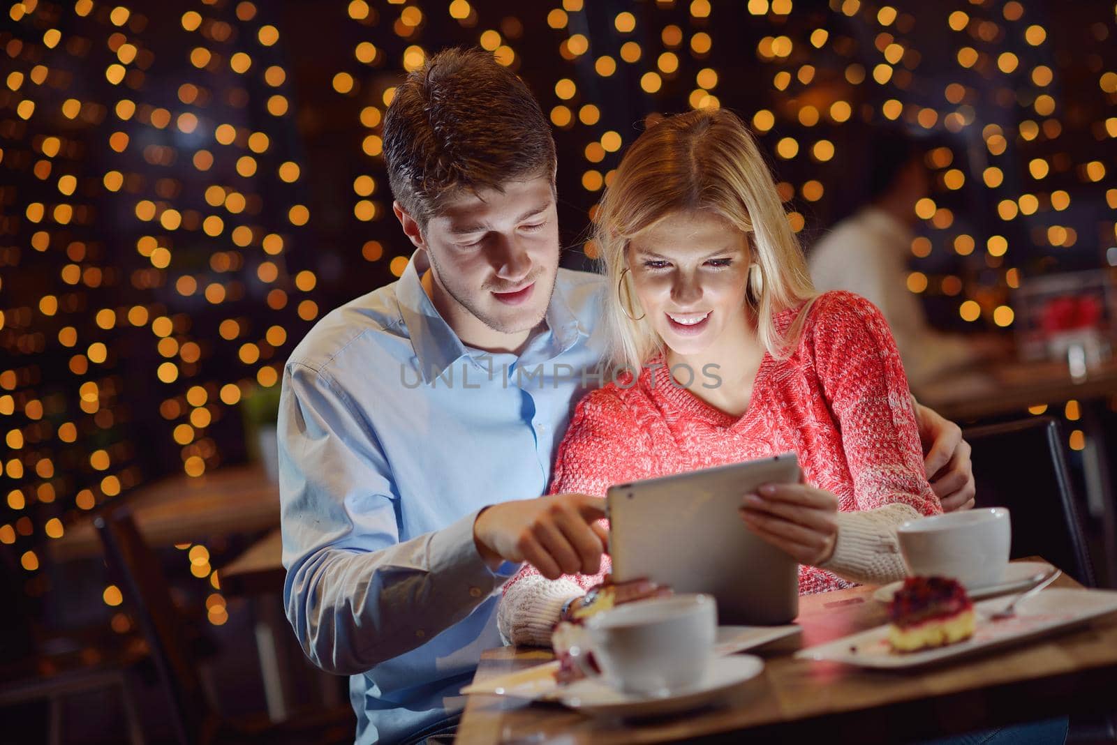 happy young couple with a tablet computer in restaurant