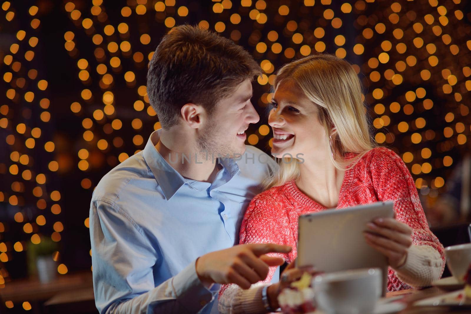 happy young couple with a tablet computer in restaurant