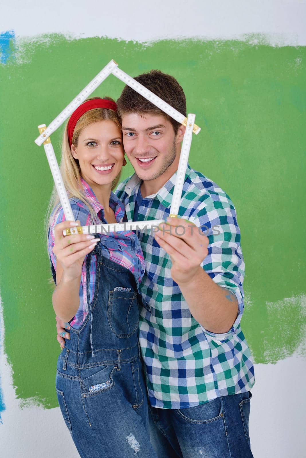 happy young couple paint in green and blue color white wall of their new home