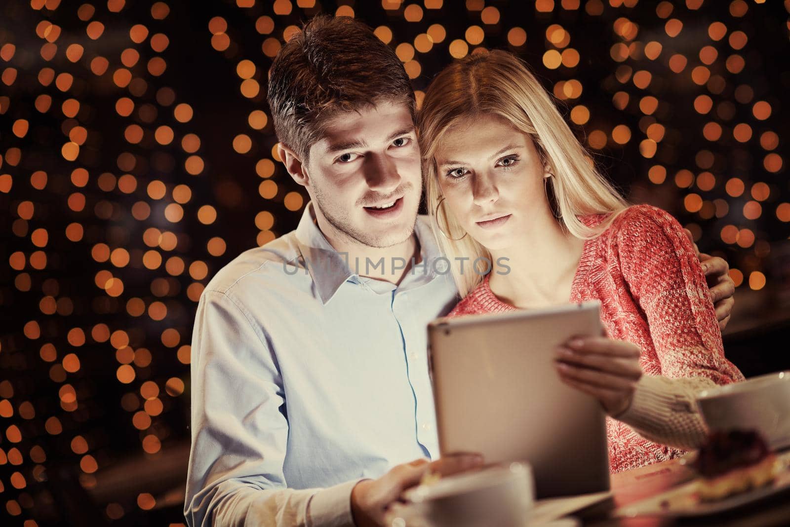 happy young couple with a tablet computer in restaurant