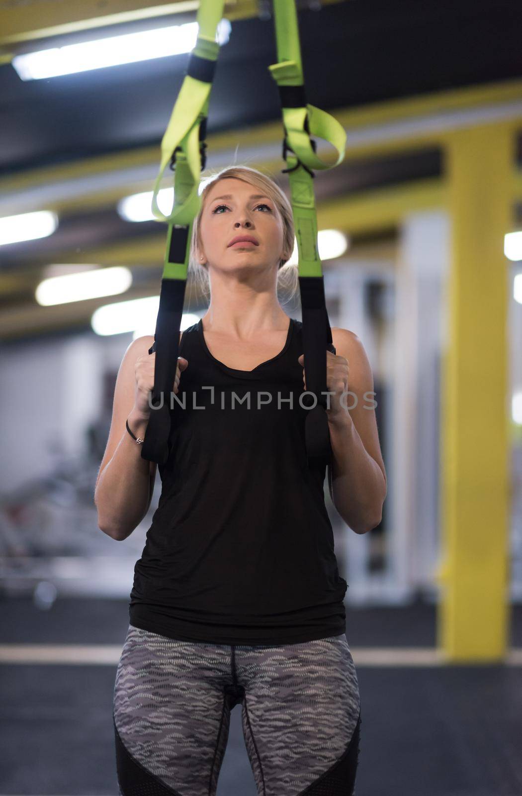 woman working out pull ups with gymnastic rings by dotshock
