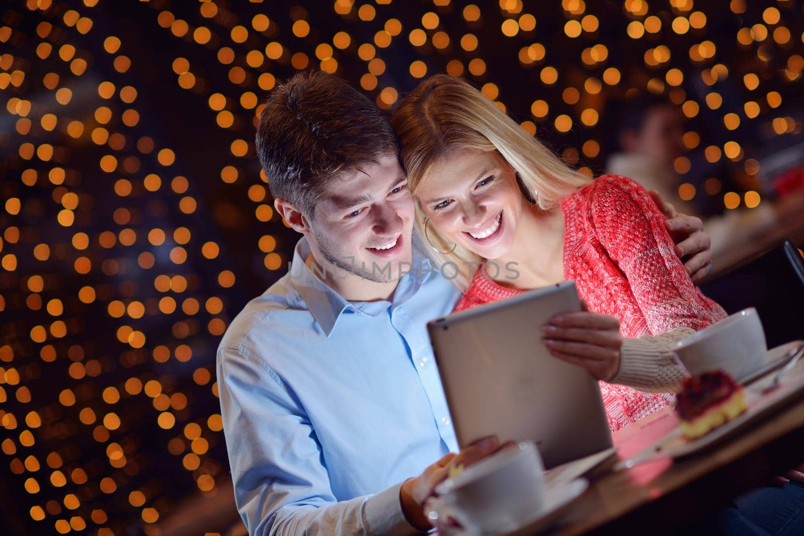 happy young couple with a tablet computer in restaurant