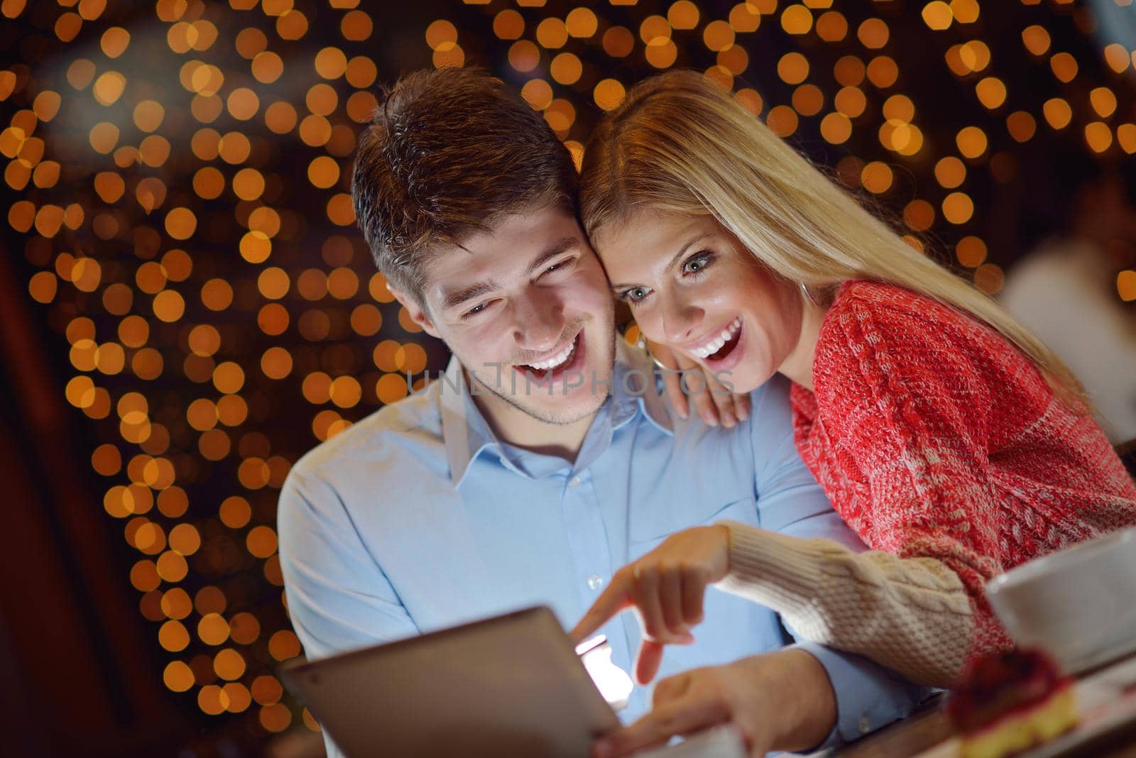happy young couple with a tablet computer in restaurant