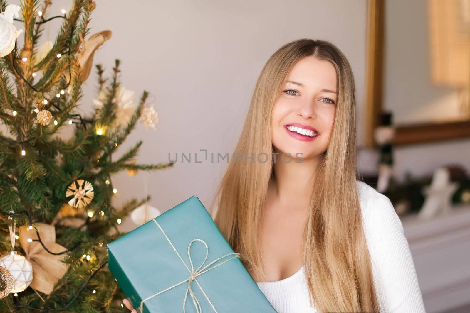 Christmas holiday and sustainable gifts concept. Happy smiling woman holding wrapped present with eco-friendly green wrapping paper by Anneleven