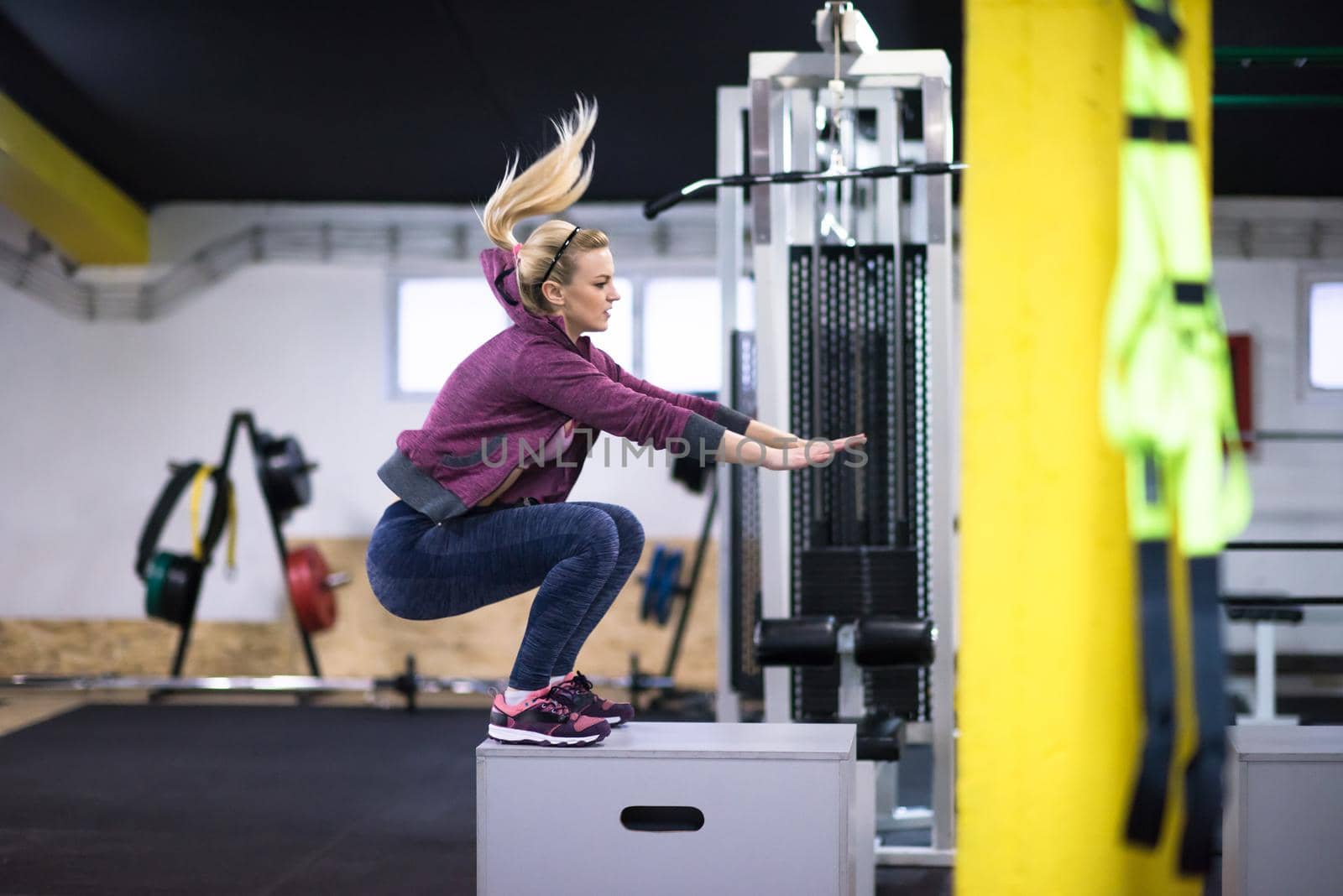 young athletic woman training  jumping on fit box at cross fitness gym