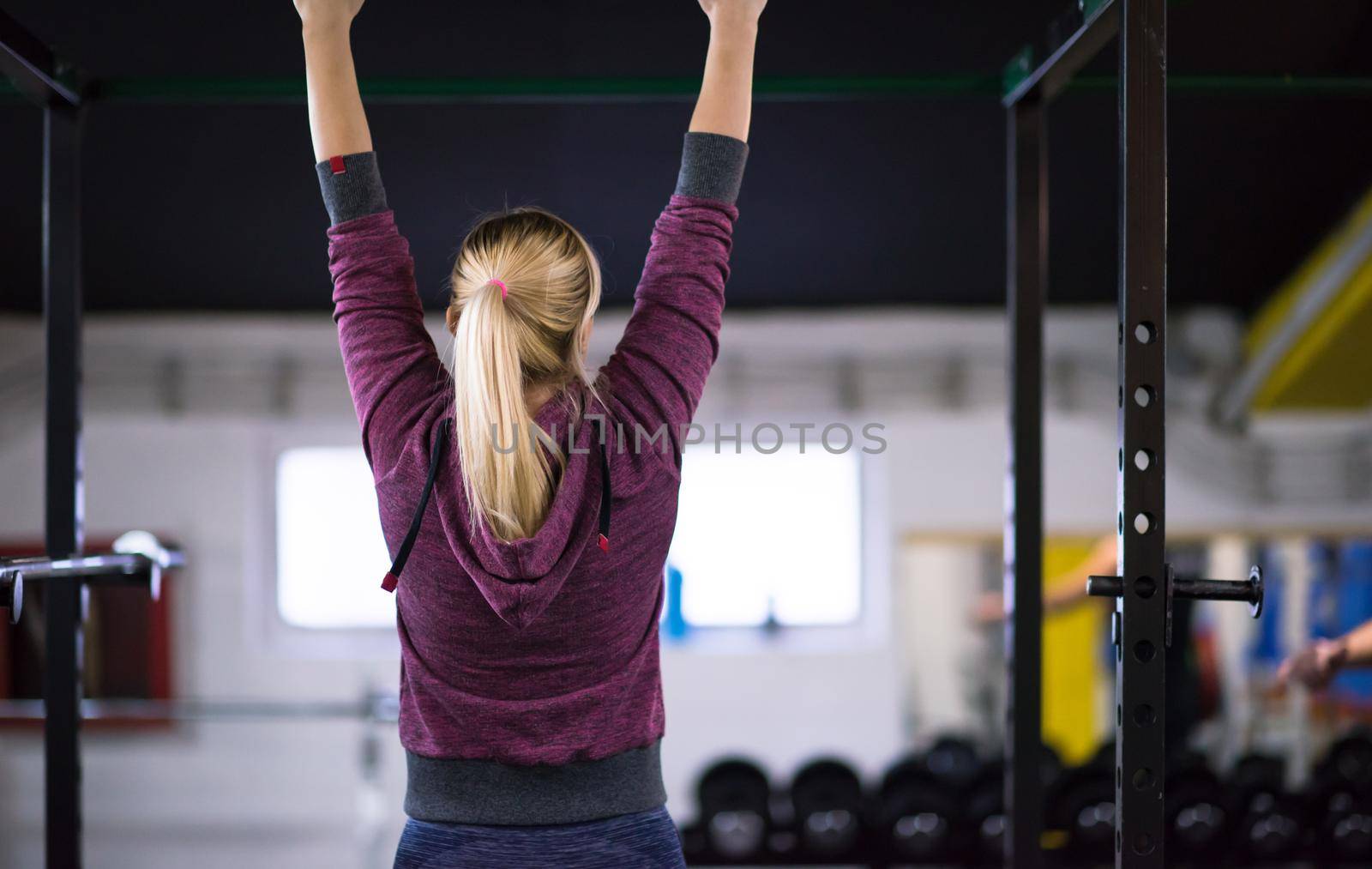 young muscular woman doing pull ups on the horizontal bar as part of Cross fitness Training