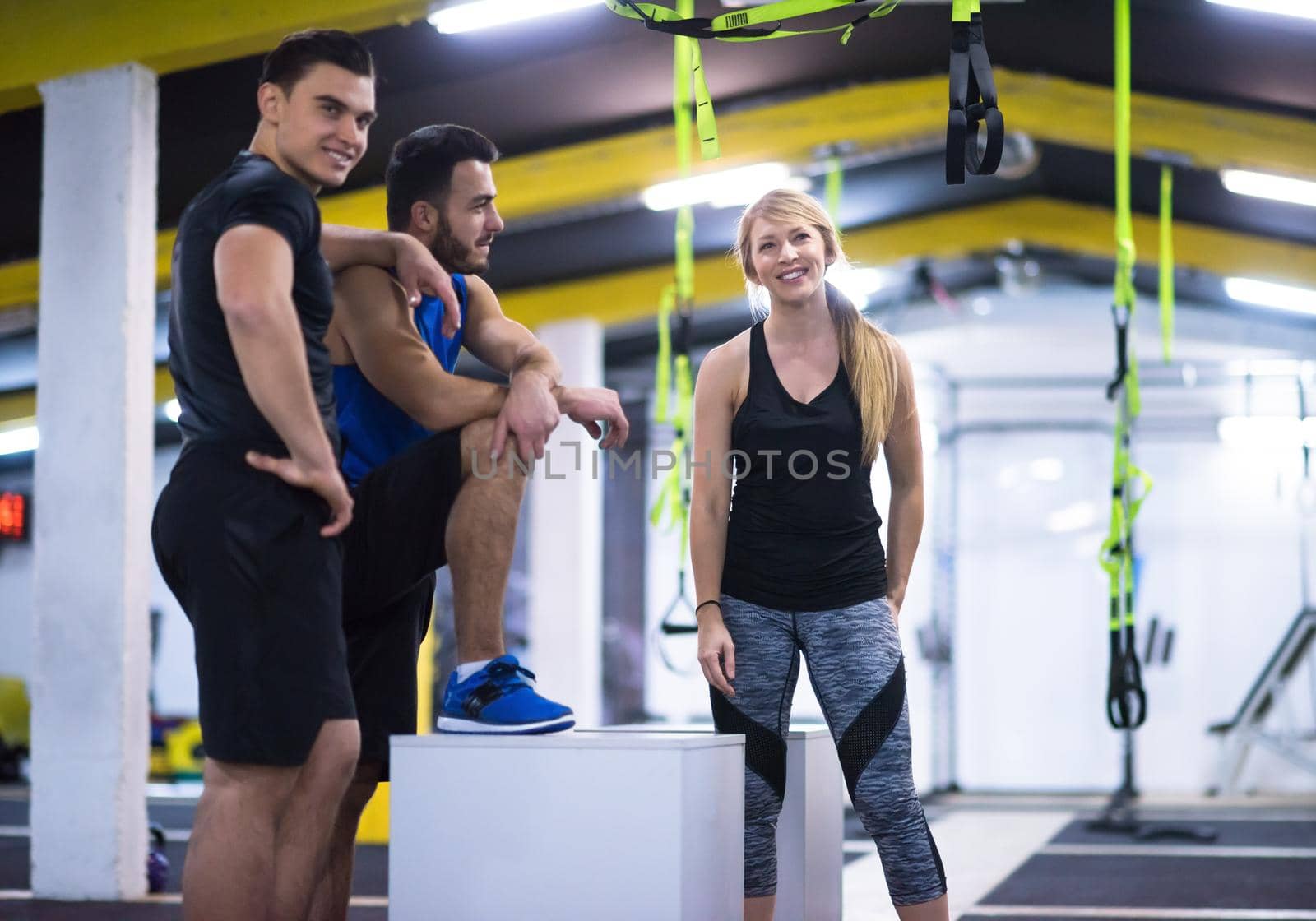 group of young healthy athletic people training jumping on fit box at cross fitness gym