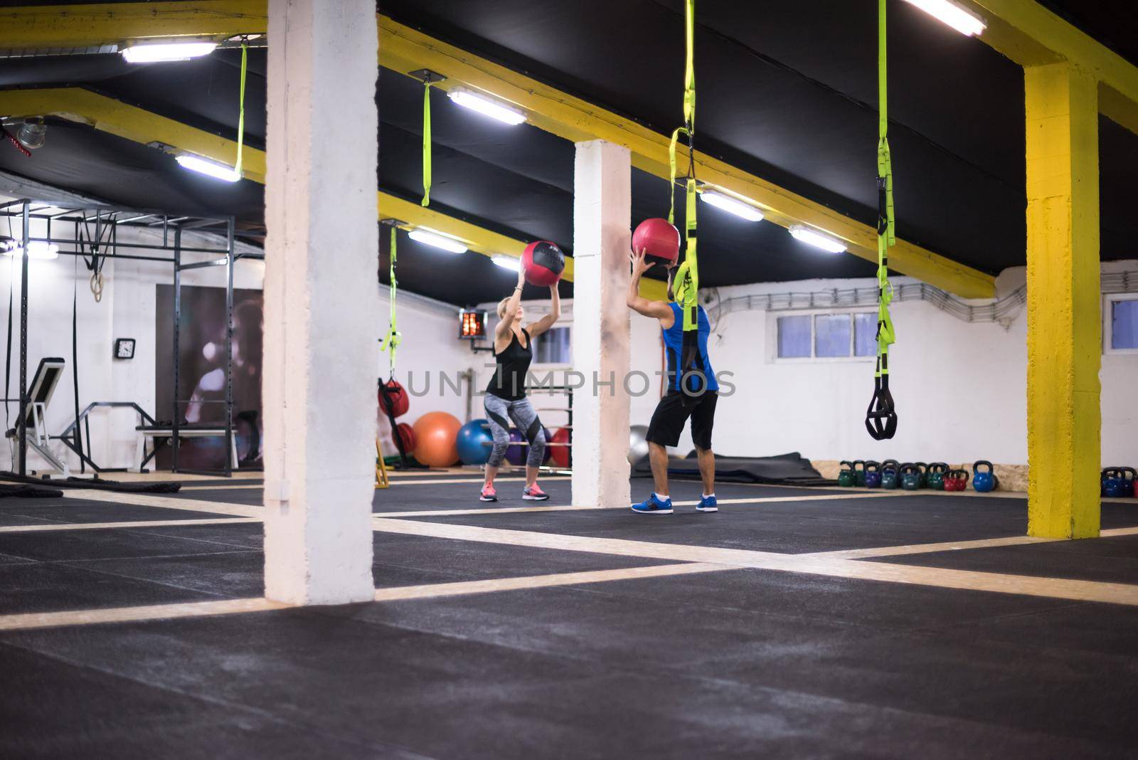 young athletes couple working out with medical ball at cross fitness gym