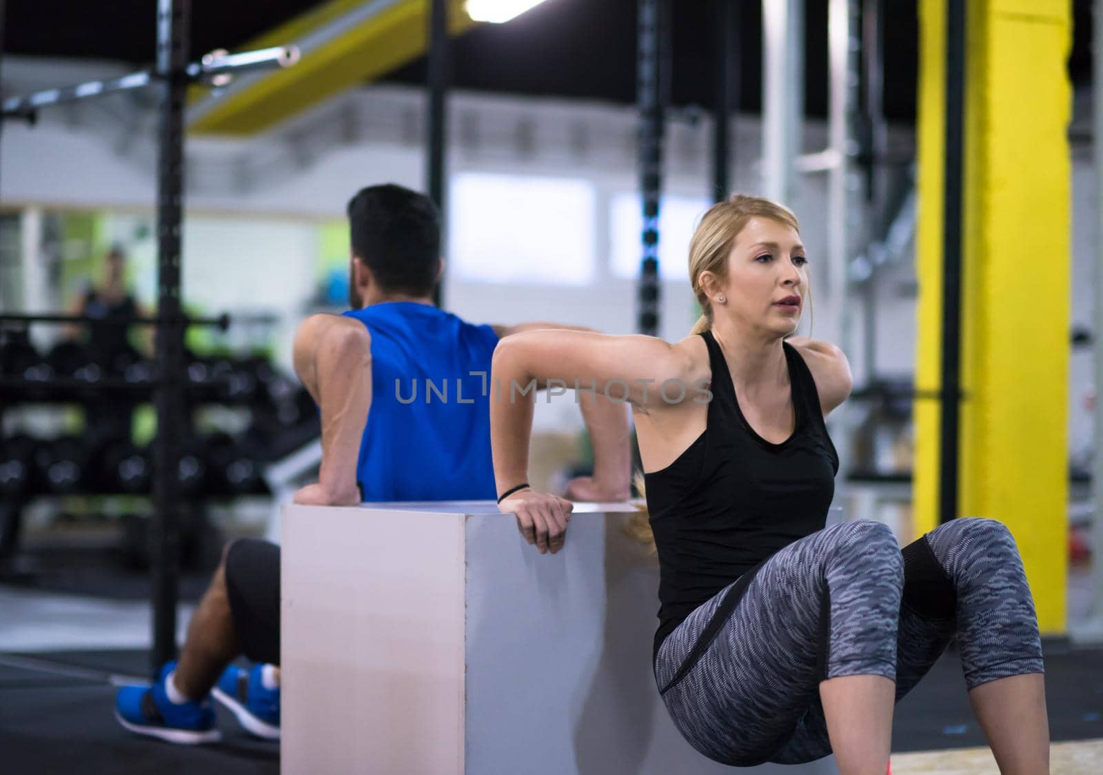 young couple athletes working out their arms using boxes at cross fitness gym