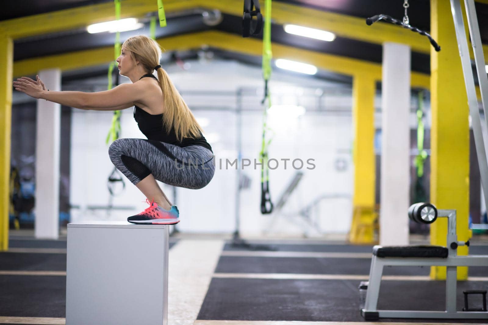 young athletic woman training  jumping on fit box at cross fitness gym