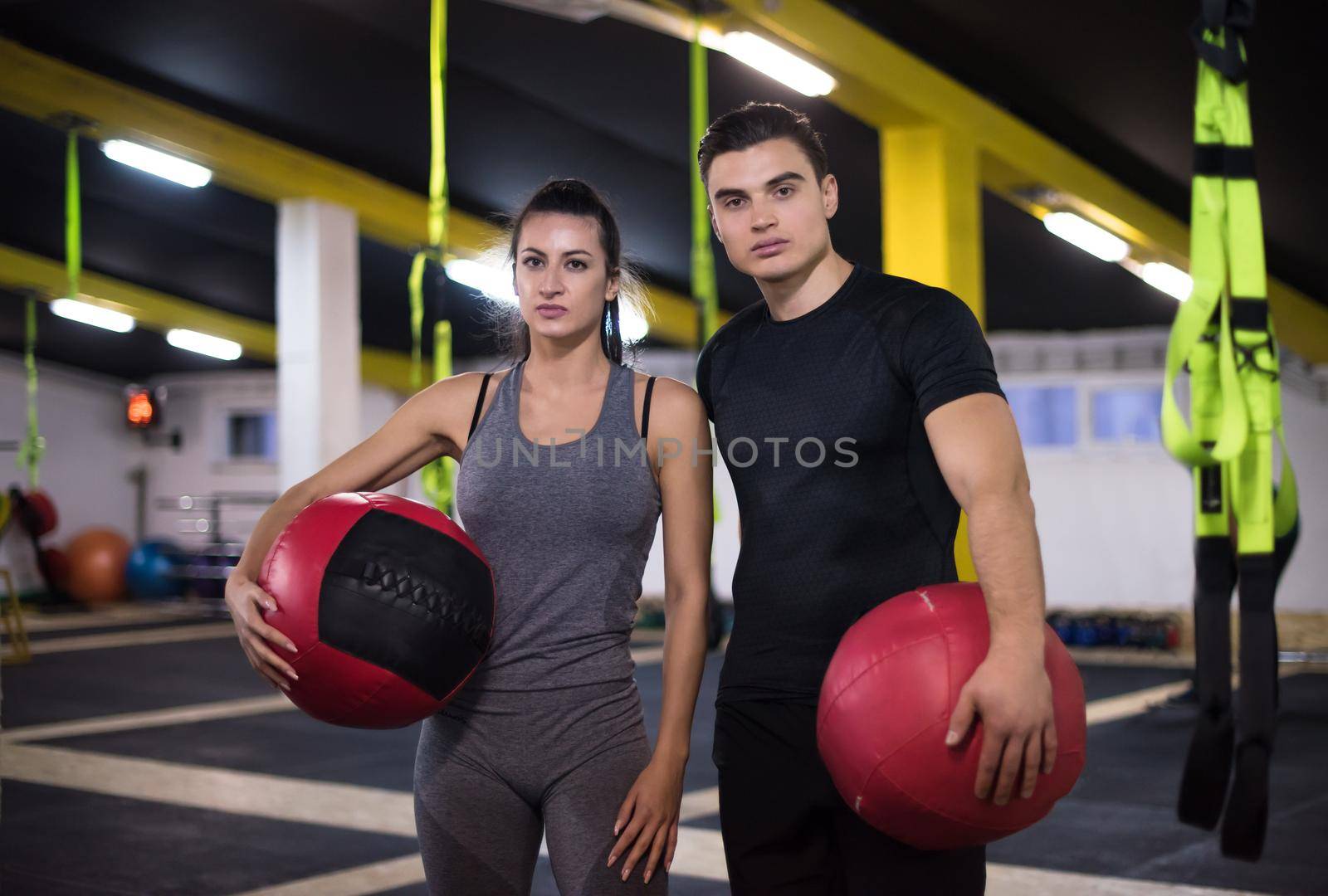 young athletes couple working out with medical ball at cross fitness gym