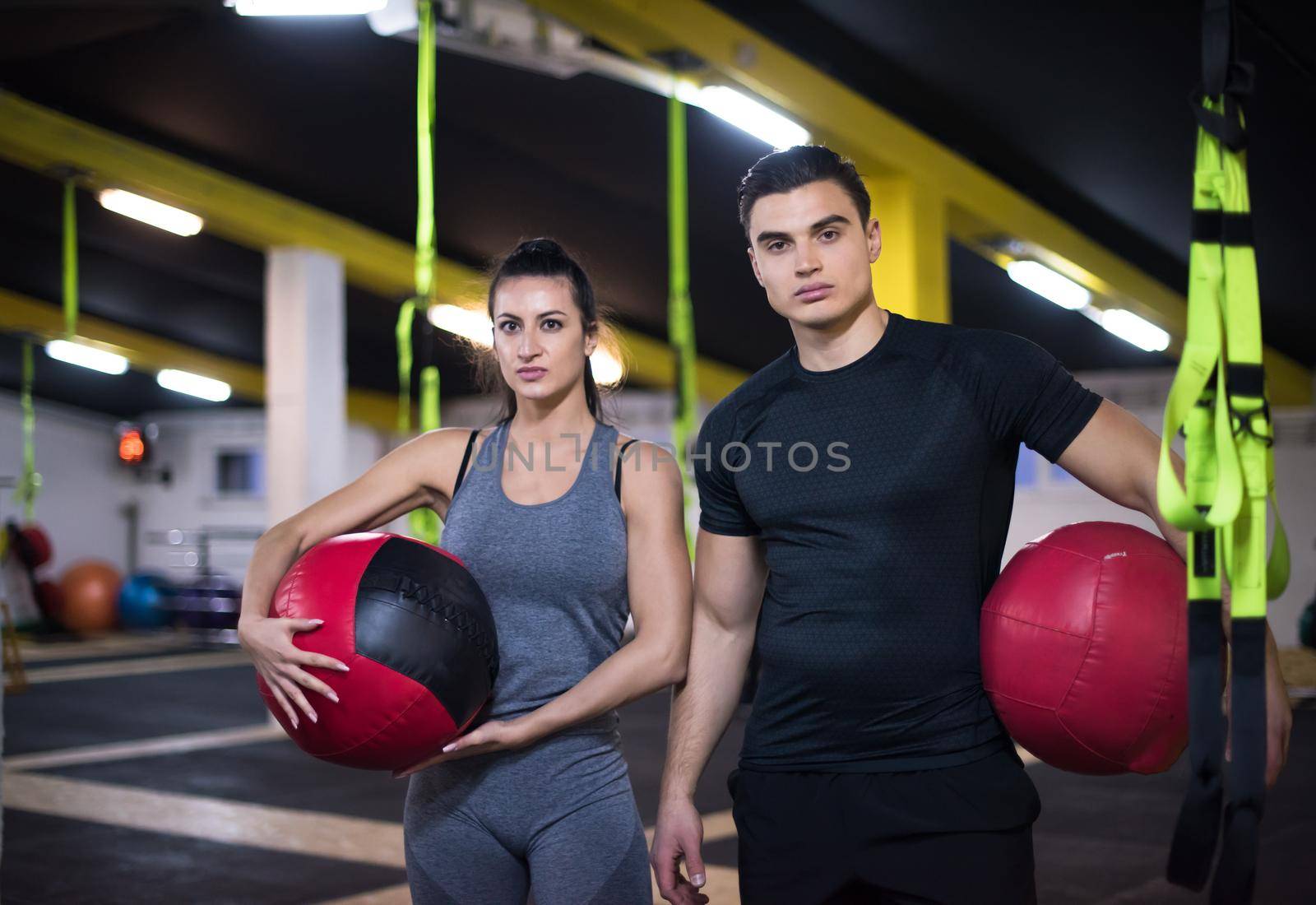 young athletes couple working out with medical ball at cross fitness gym