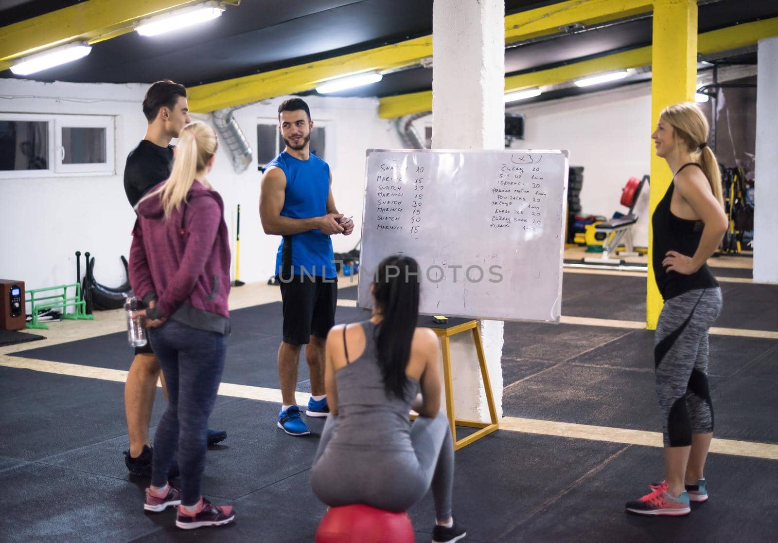 Training course.group of young athletes getting instructions from trainer before exercise at cross fitness gym