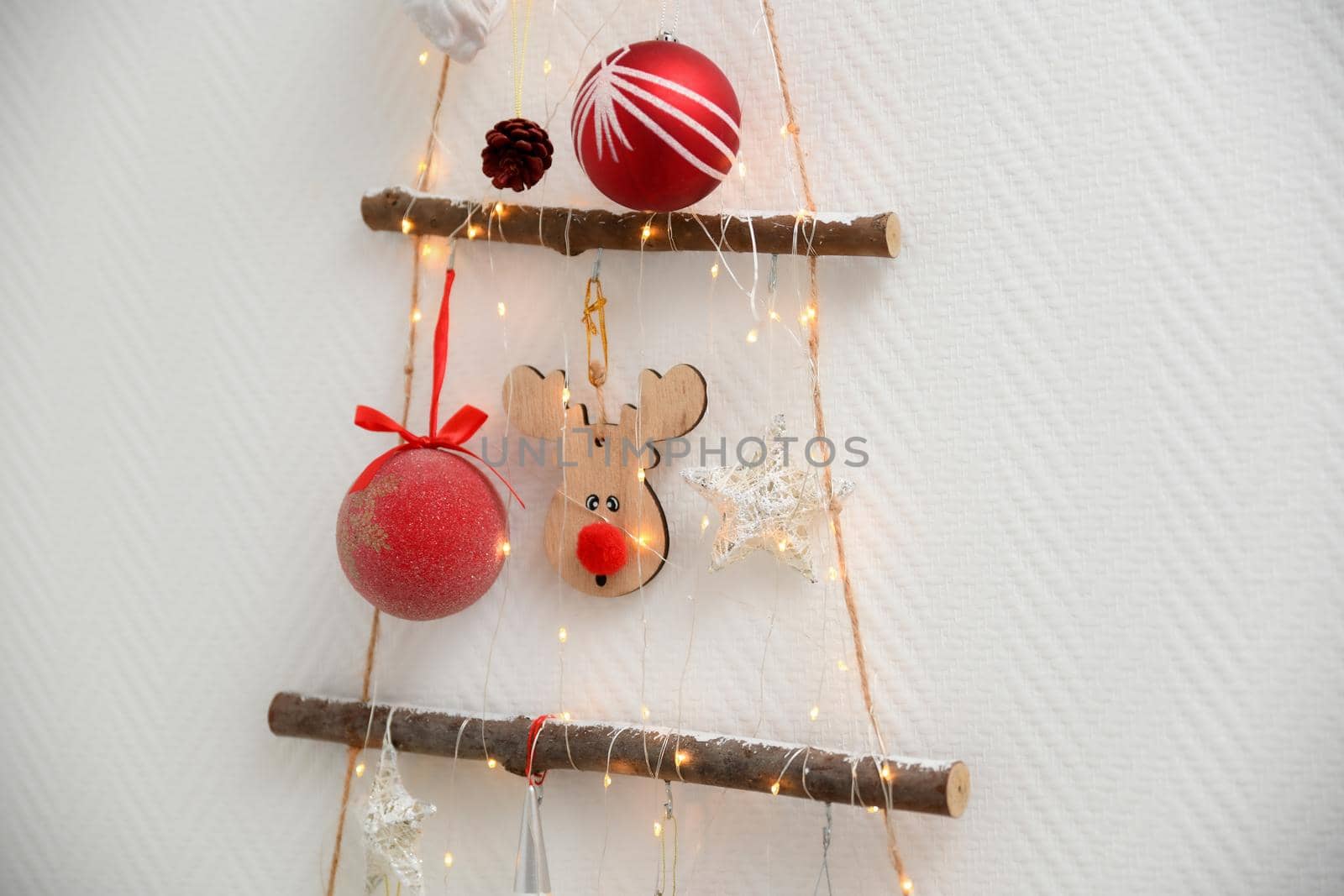 Handmade wooden Christmas tree with toys hanging on the wall