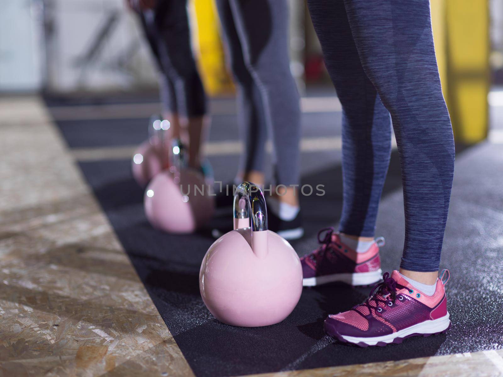 group of healthy young athletes doing exercises with kettlebells at crossfitness studio