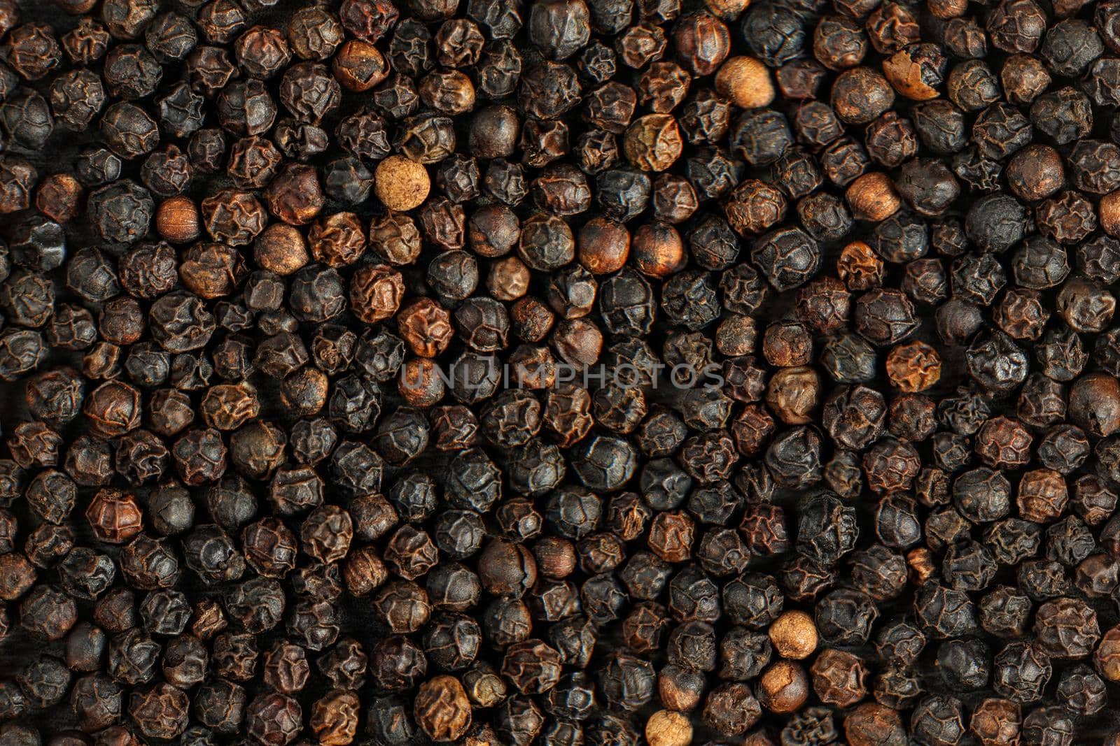 Detail macro of heap of dried black pepper (Piper nigrum) peppercorns.