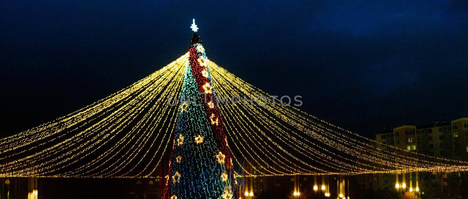 Long exposure night shot of a uniquely decorated main Christmas tree in the square after rain with reflection. by Matiunina