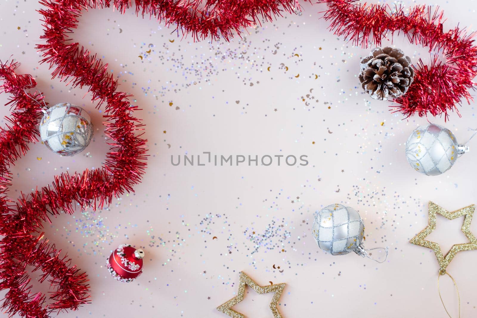 Flat lay xmas composition with empty space. Red tinsel, golden stars, silver Christmas balls and glitter with bokeh lights. New Year backplate for your design or postcard. Happy holidays concept